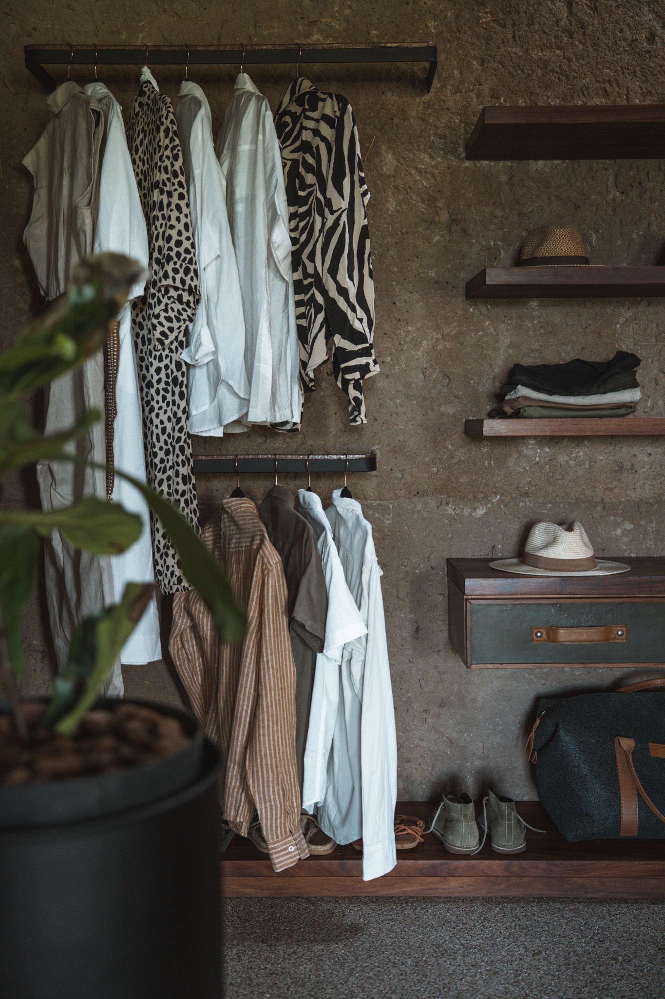 Modern closet organization with animal print clothing and wooden shelving against textured wall.