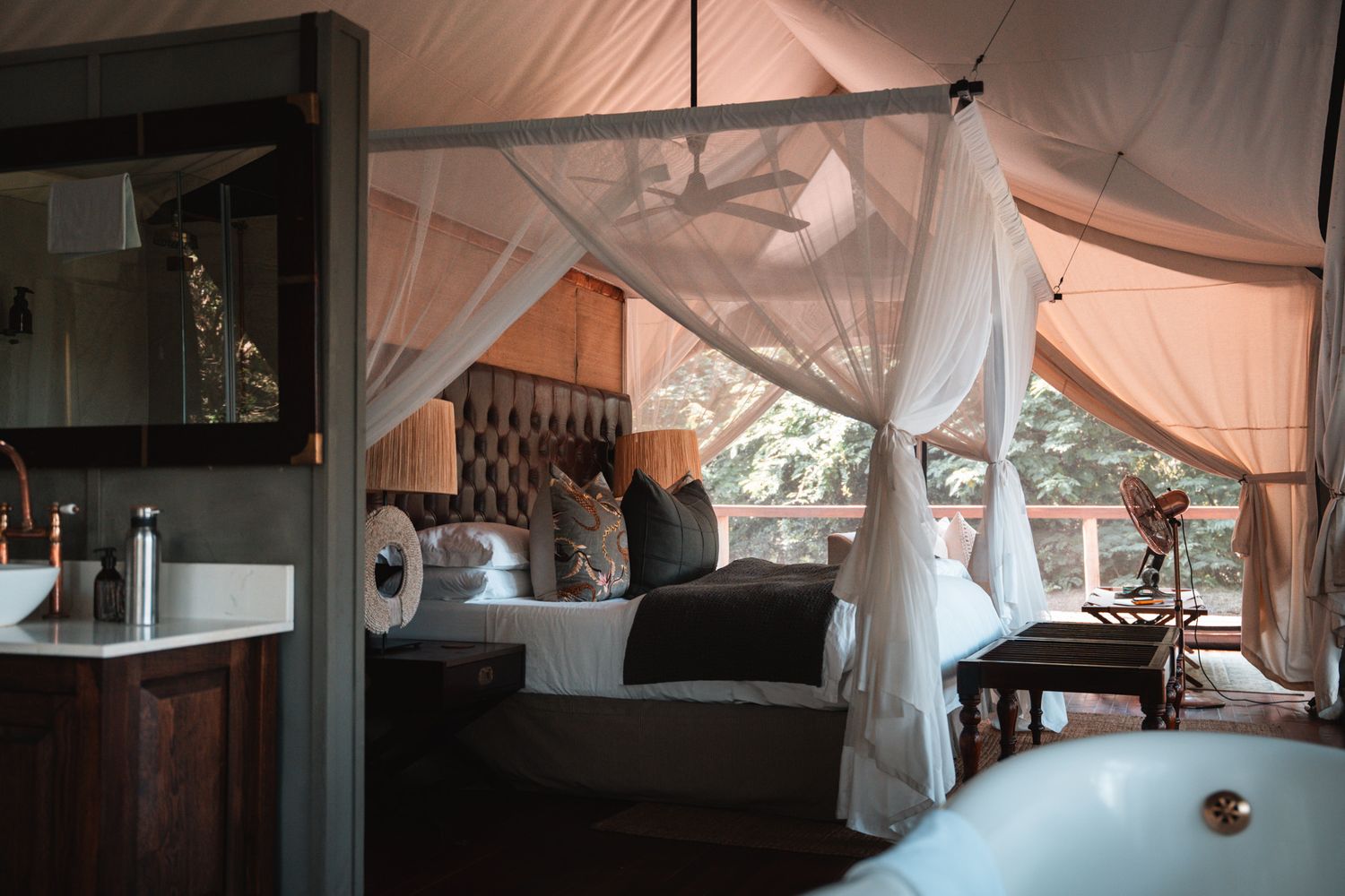 Elegant glamping tent interior with draped white fabric and plush bedding.