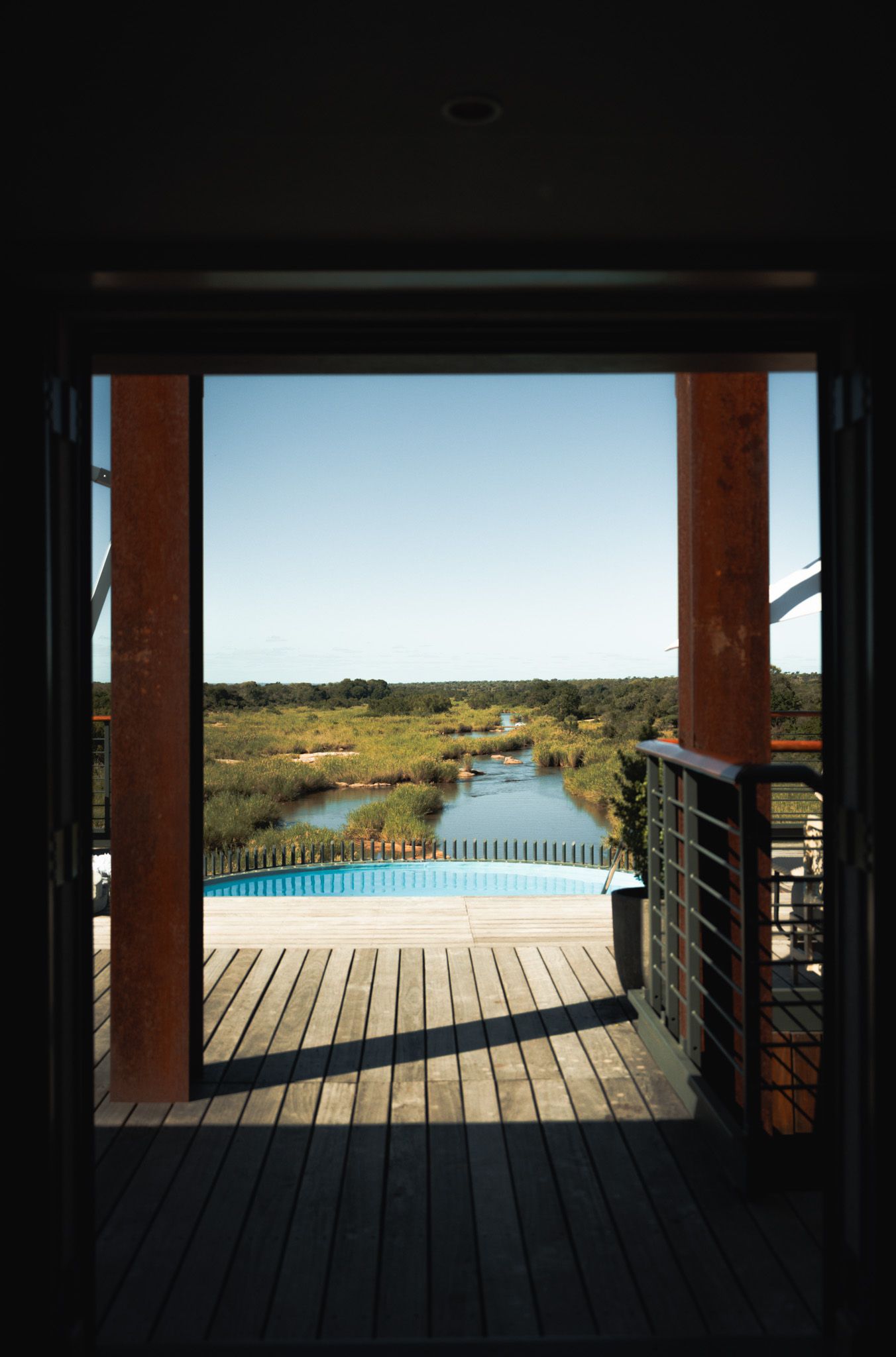 Covered walkway framing view of infinity pool overlooking natural landscape.