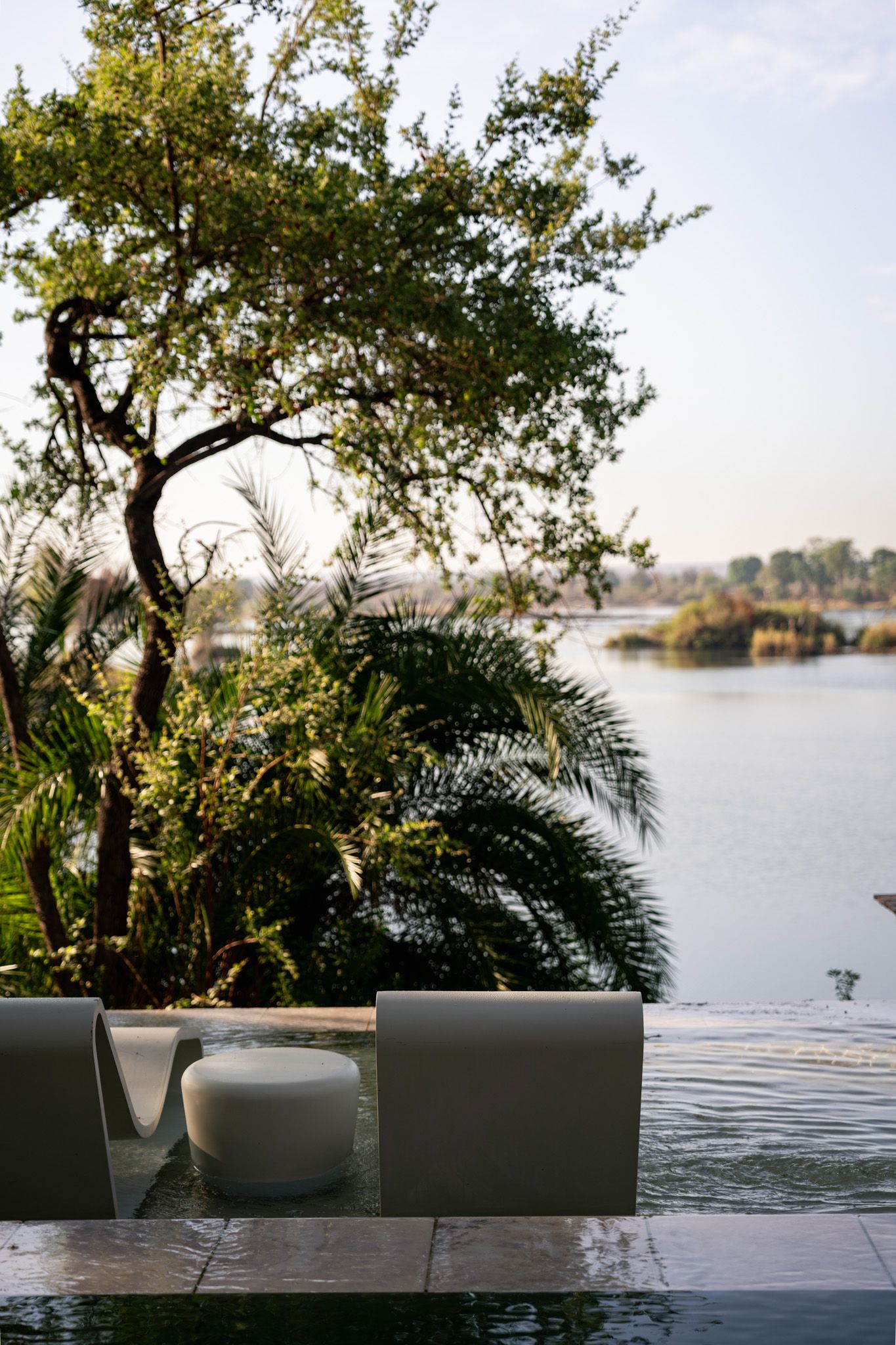 Lakeside seating area with modern chairs overlooking calm waters and lush vegetation.
