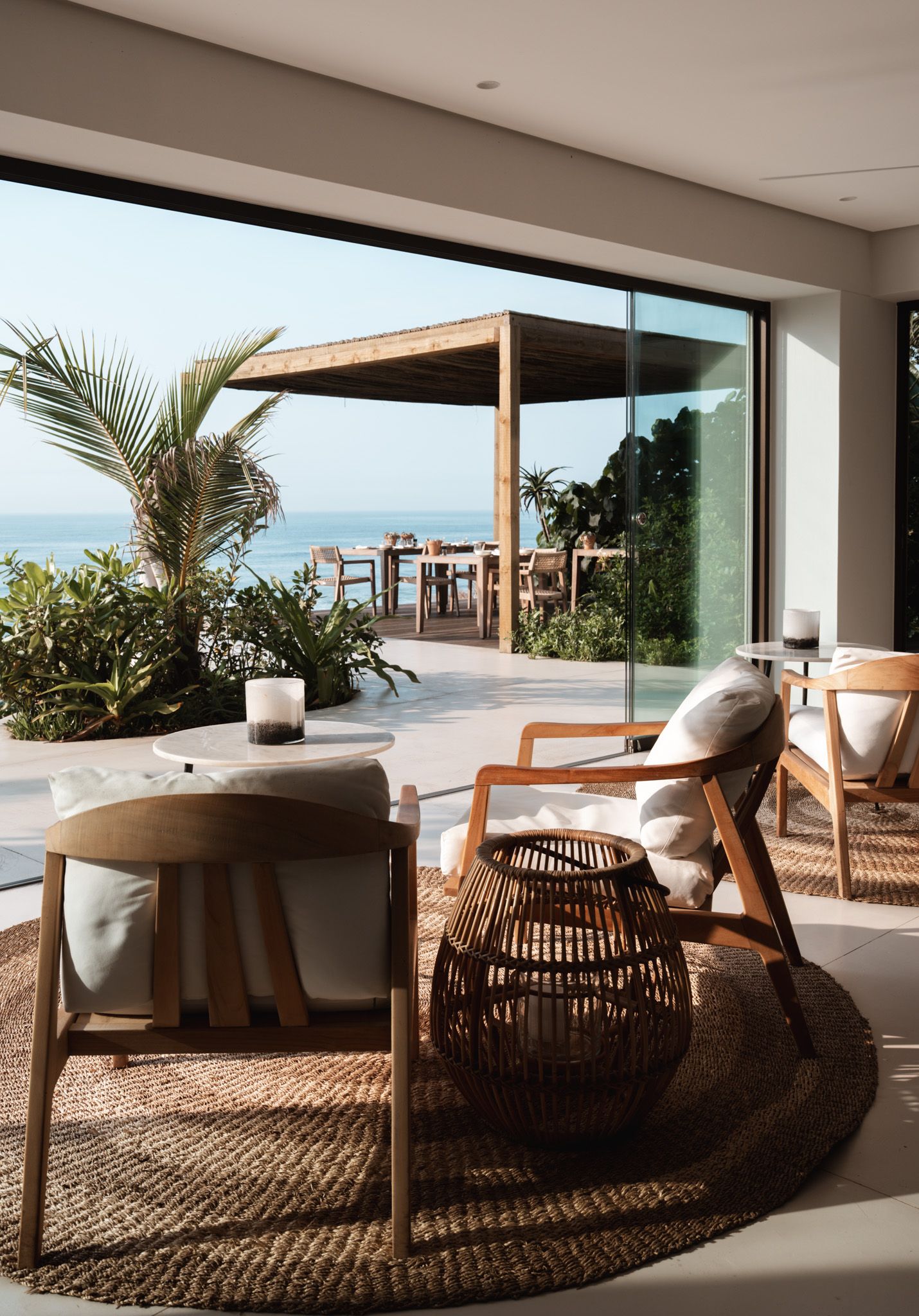 Coastal living room with woven furniture and ocean view terrace.
