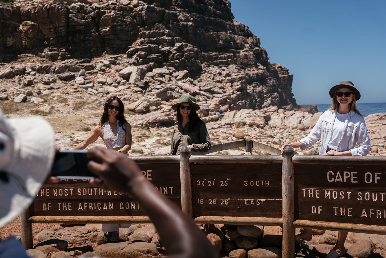 Tourists at wooden signs marking the location of Cape of Good Hope.