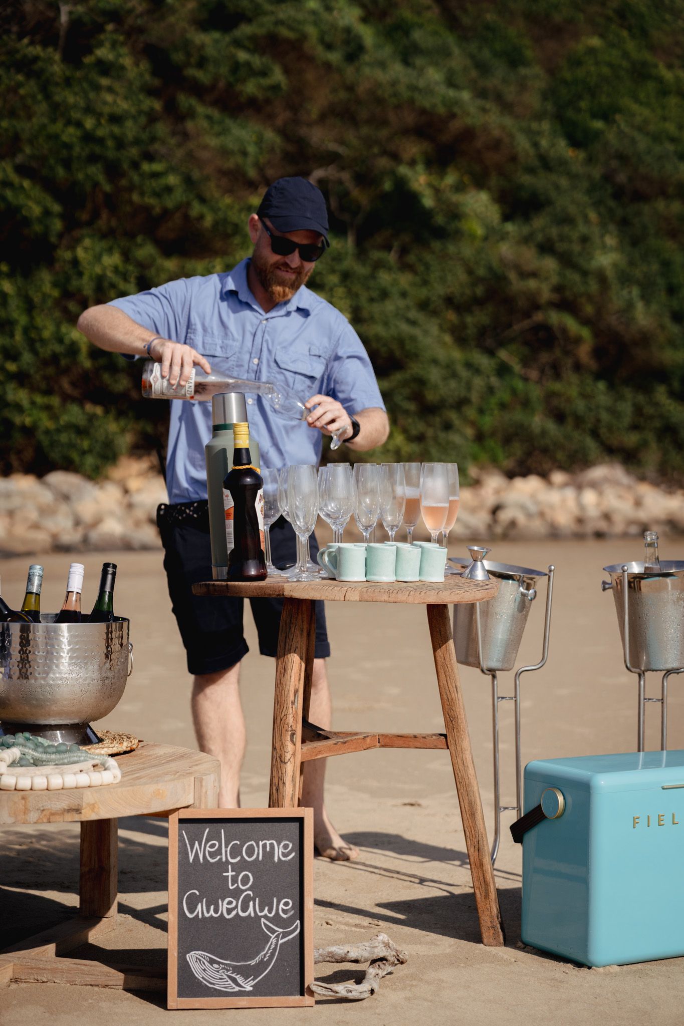Bartender pouring drinks at outdoor bar setup with Welcome to Cuveebyte sign.