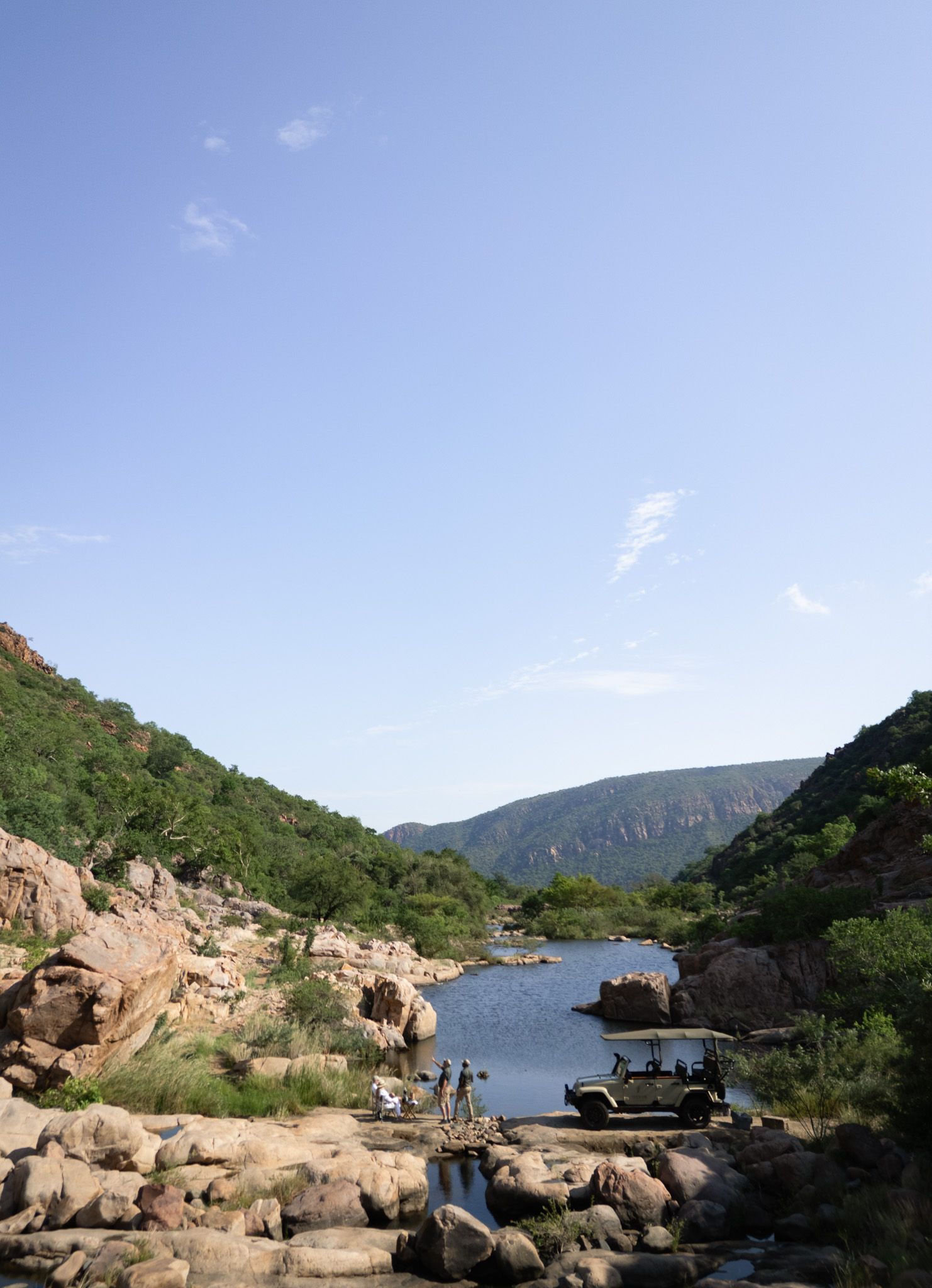Rocky river landscape with safari vehicle traversing rugged terrain.