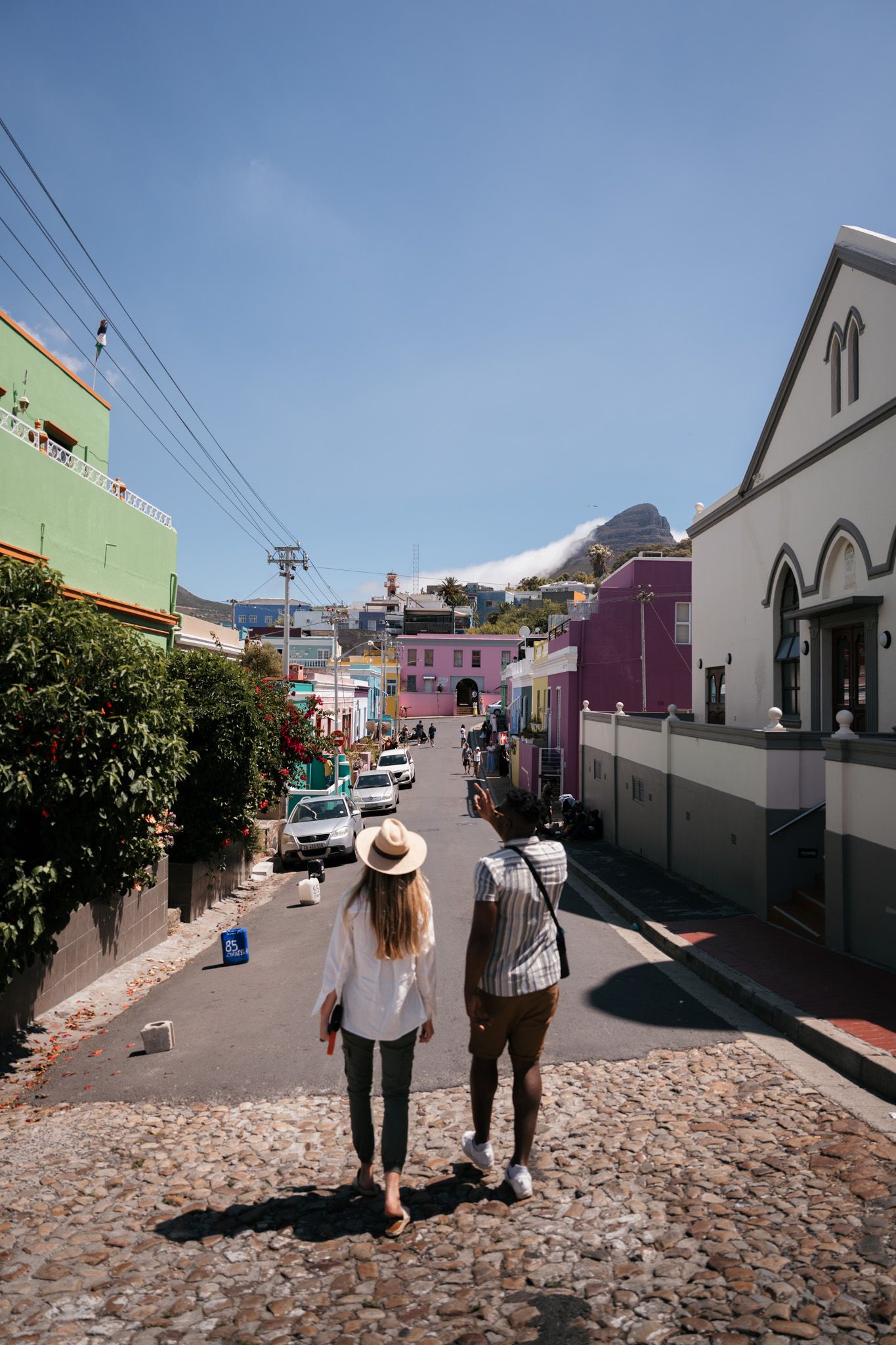 Colorful cobblestone street lined with vibrant houses in a coastal town.
