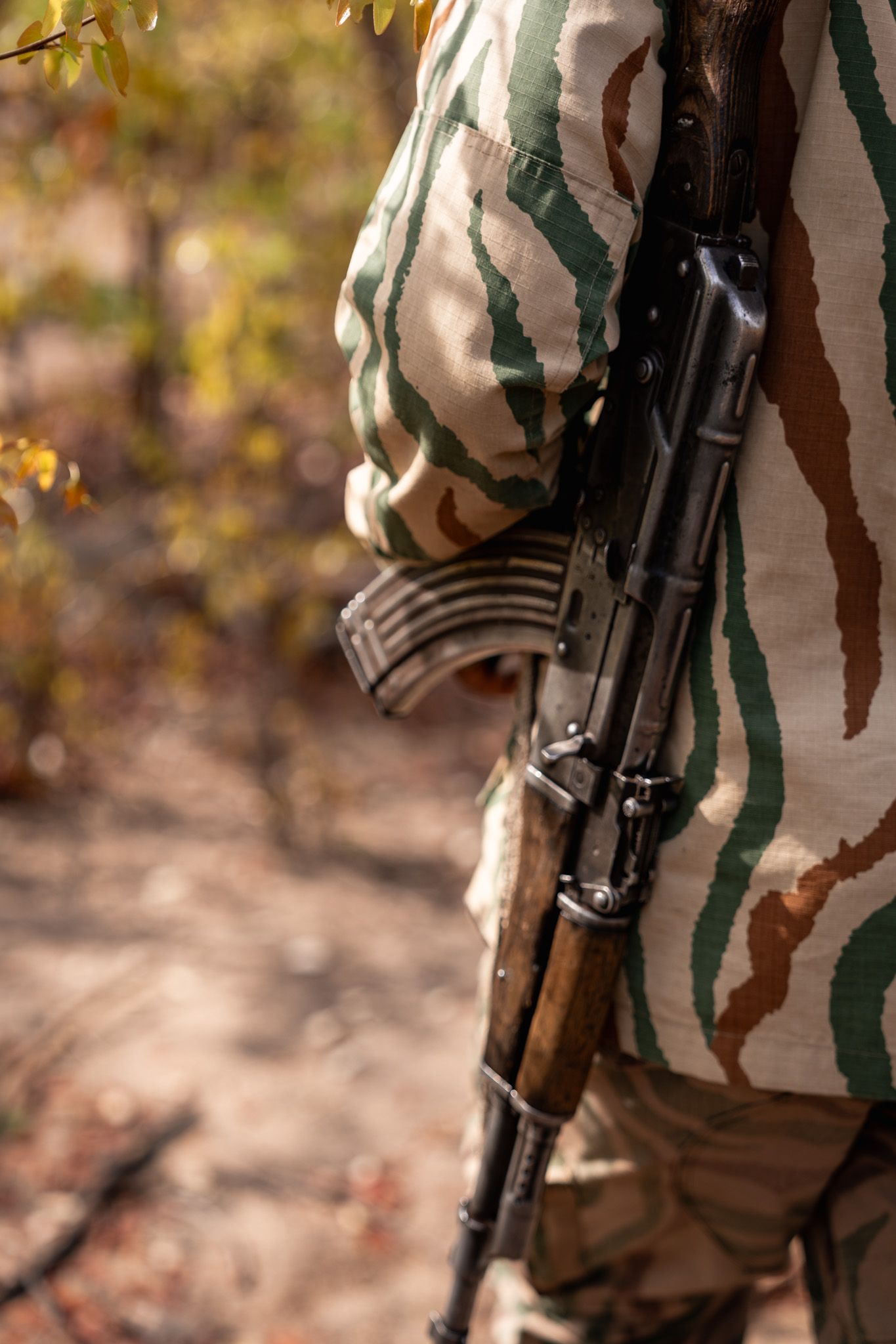 Close-up of camouflage uniform and rifle equipment used for wildlife protection.