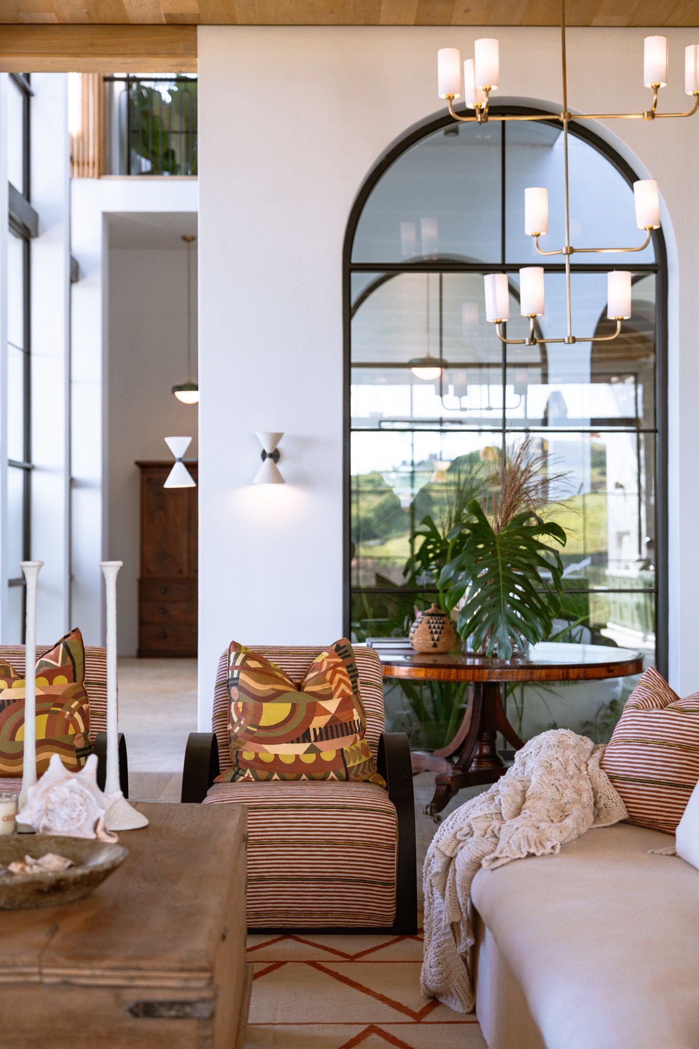 Elegant living area with arched mirror, coastal decor, and abundant natural light.