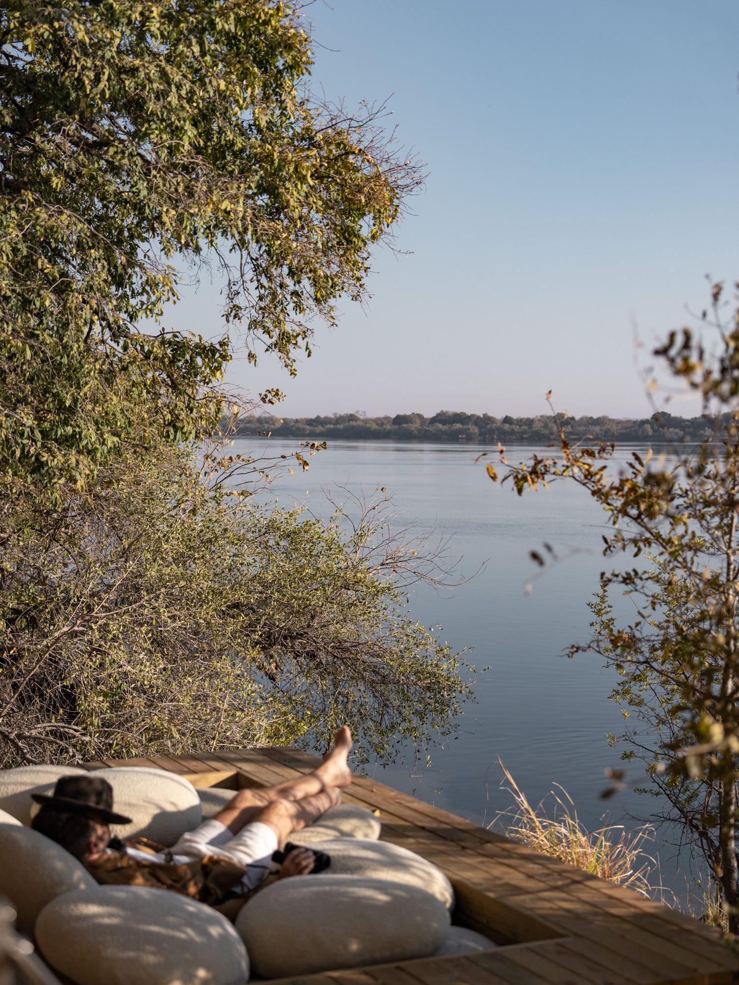 A peaceful lakeside scene with cushions and personal items arranged on a wooden deck.