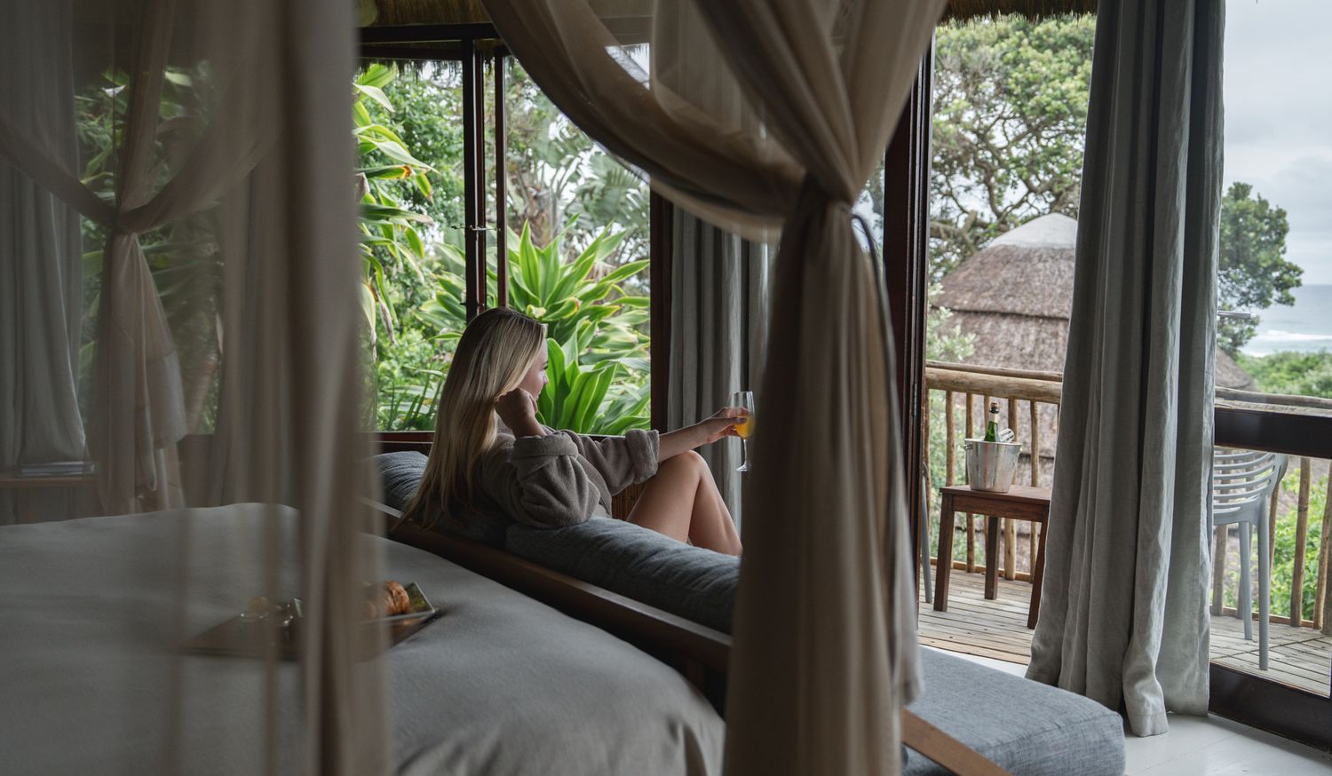 Relaxing view of a luxury bedroom with canopy bed and tropical balcony view.
