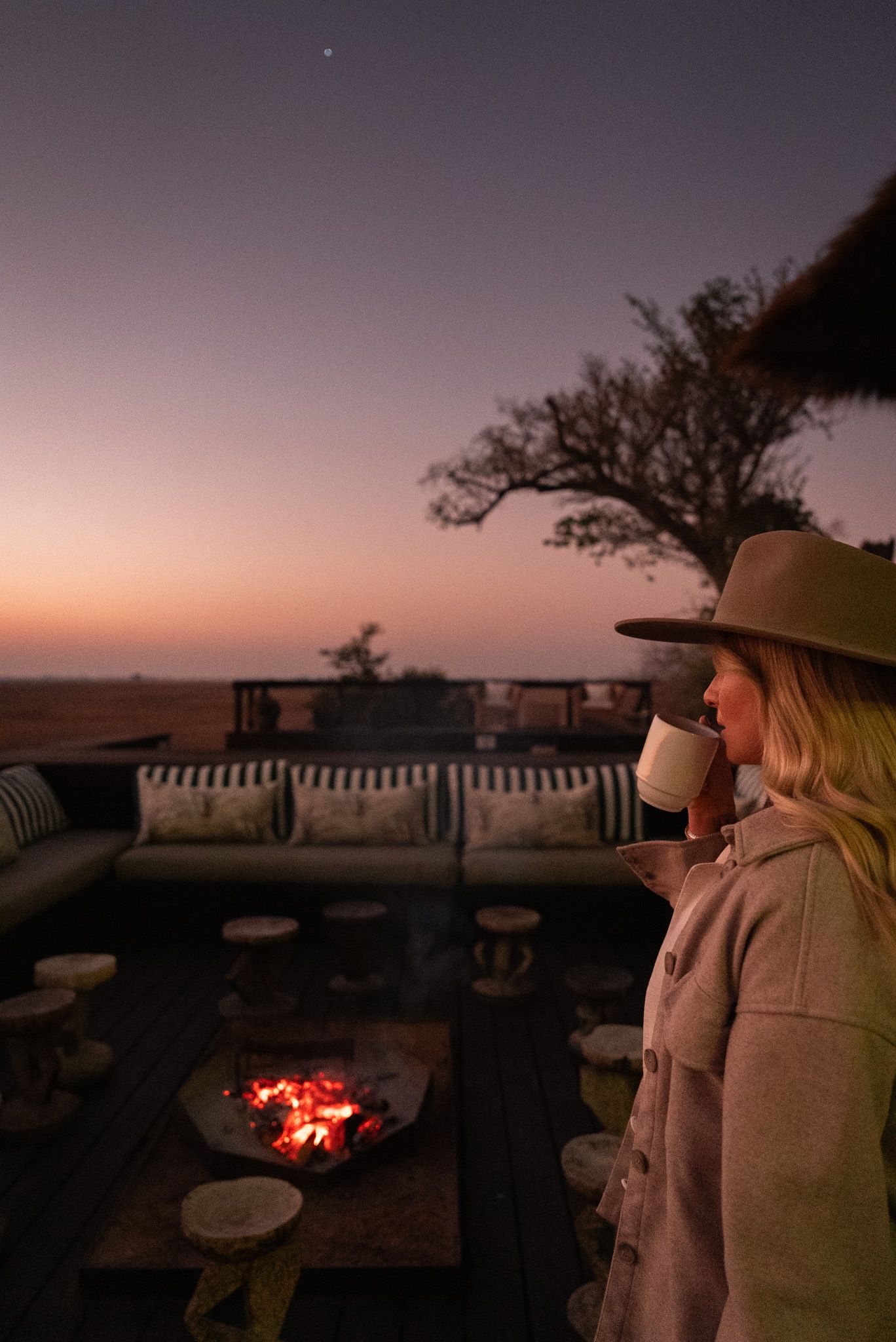 Evening gathering around a campfire with safari hats and warm lighting at dusk.