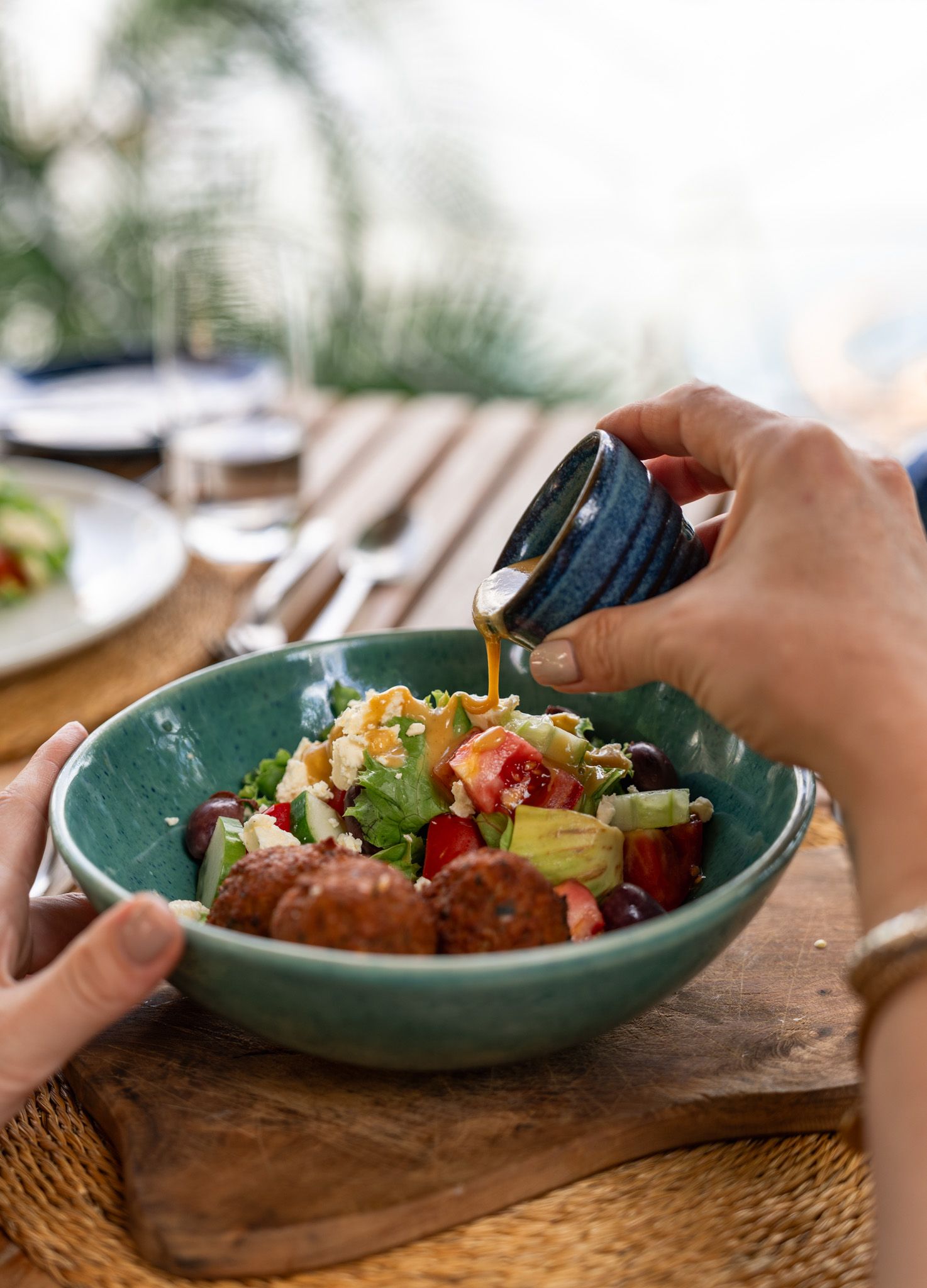 Colorful dish being served in a teal ceramic bowl on wooden table.