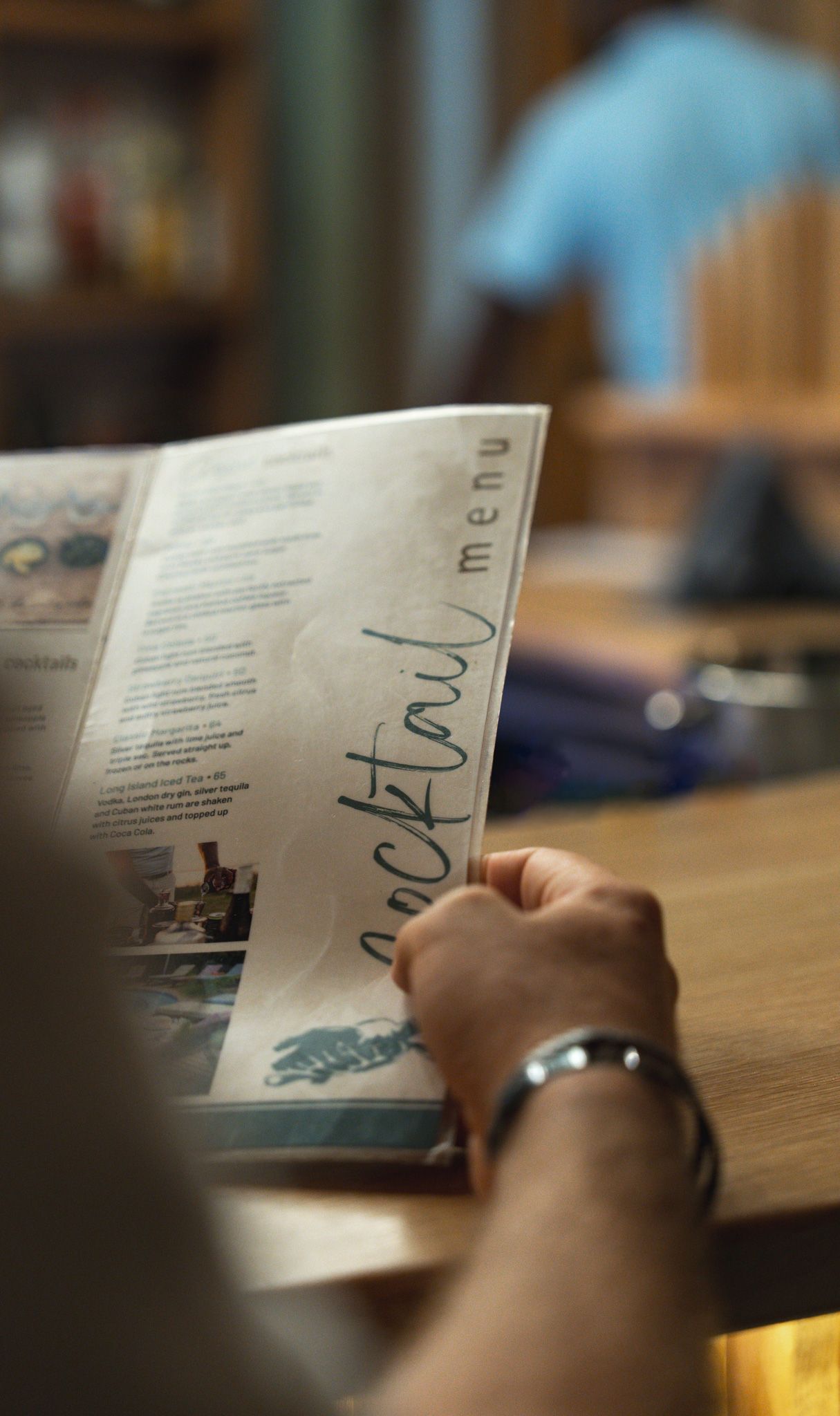 Hands holding and writing in an open booklet or brochure on a wooden table.