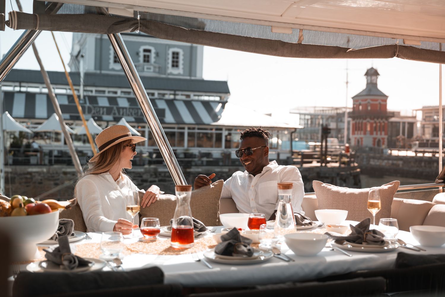 Elegant outdoor dining scene at a waterfront restaurant with historic buildings in view.