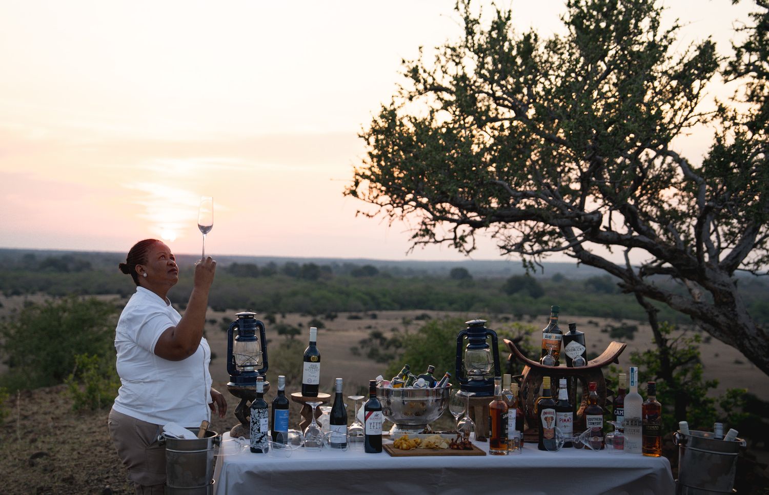 Sunset gathering with wine bottles and glasses displayed on outdoor tables.