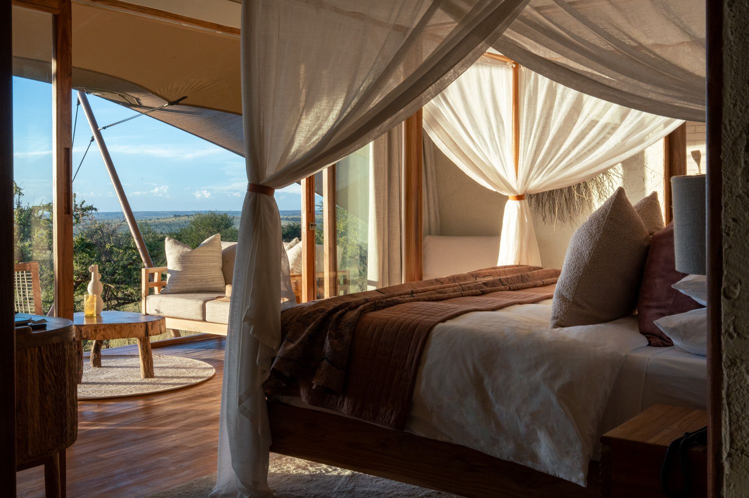 Luxurious canopy bed with white drapes overlooking a scenic outdoor view.