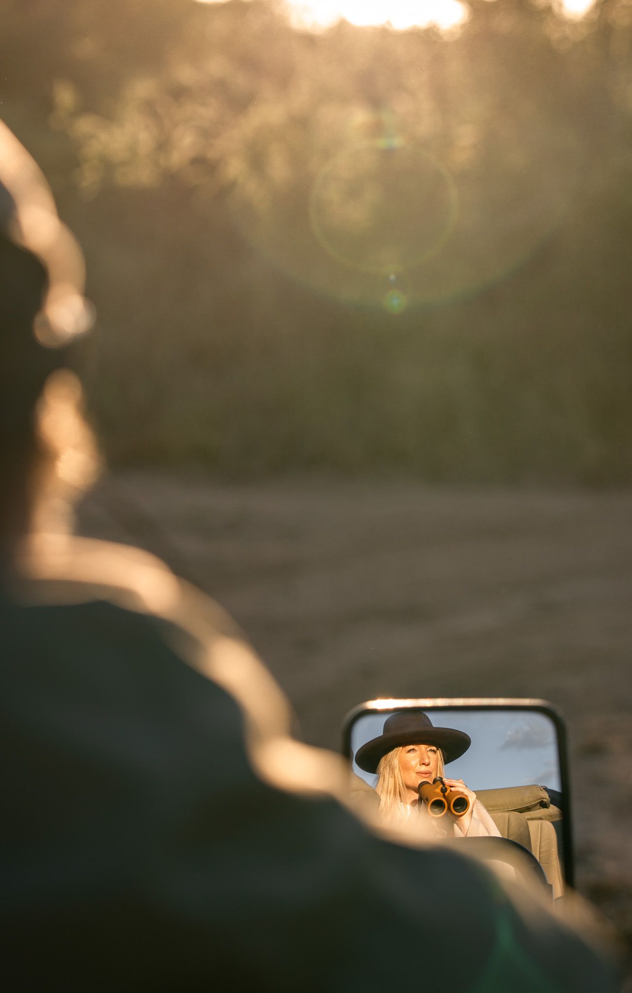 Side mirror reflections of a safari vehicle at sunset with warm golden lighting.