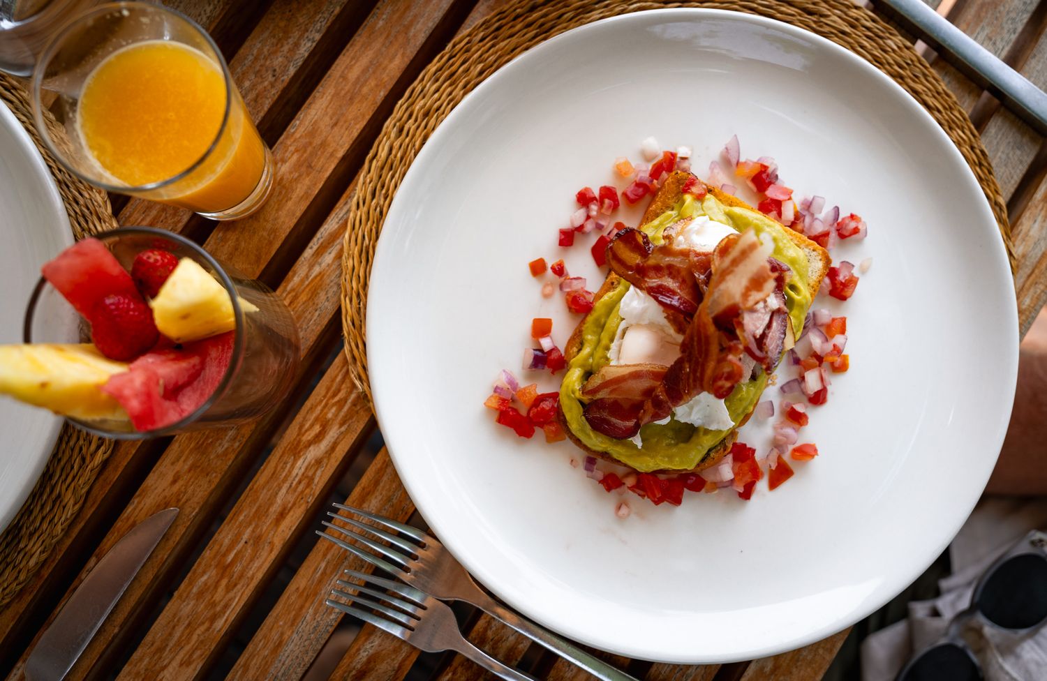 Row of elegant white plates with colorful garnishes on wooden table.