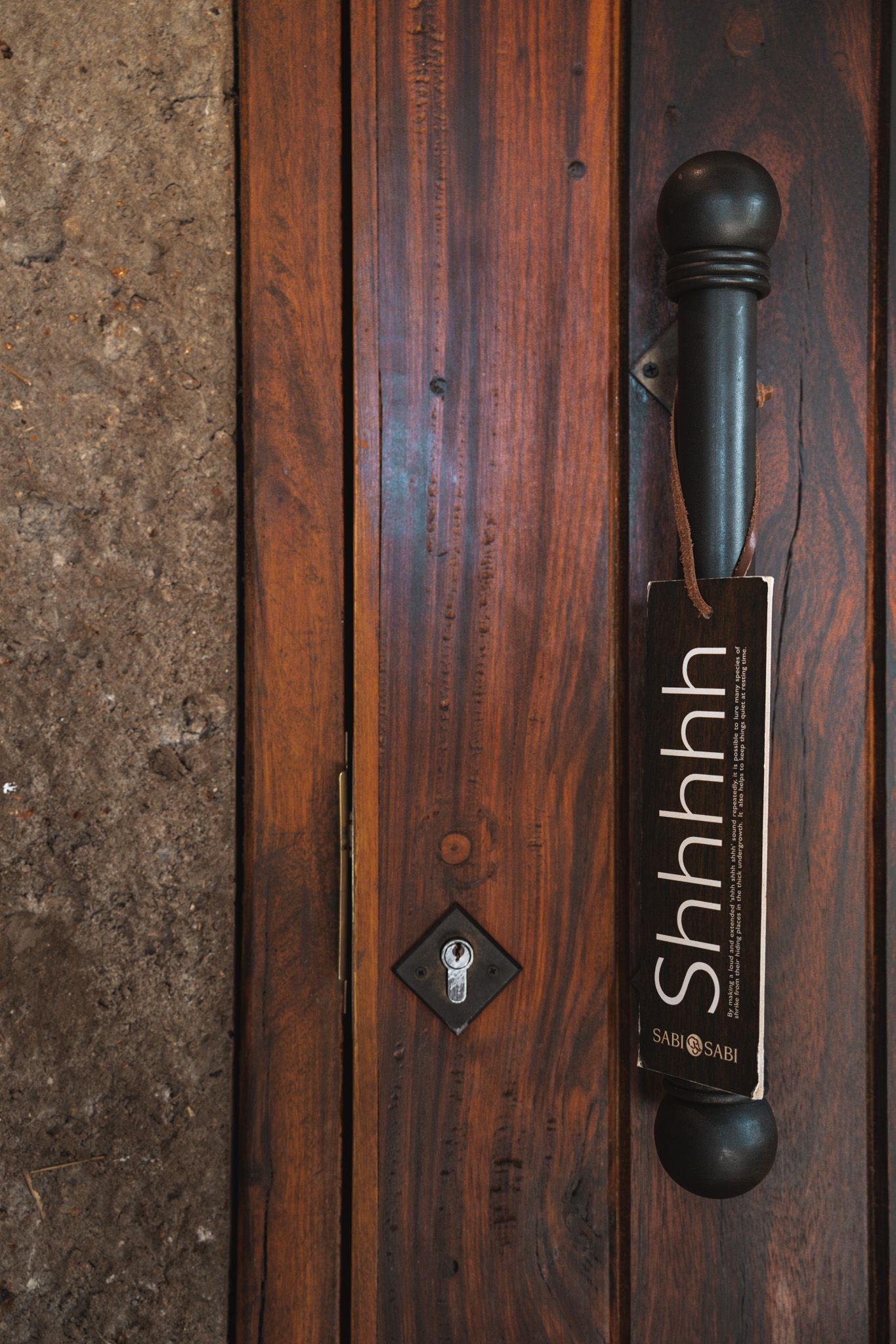 Wooden door handle with 'Shhhh' text engraved on dark stained wood.