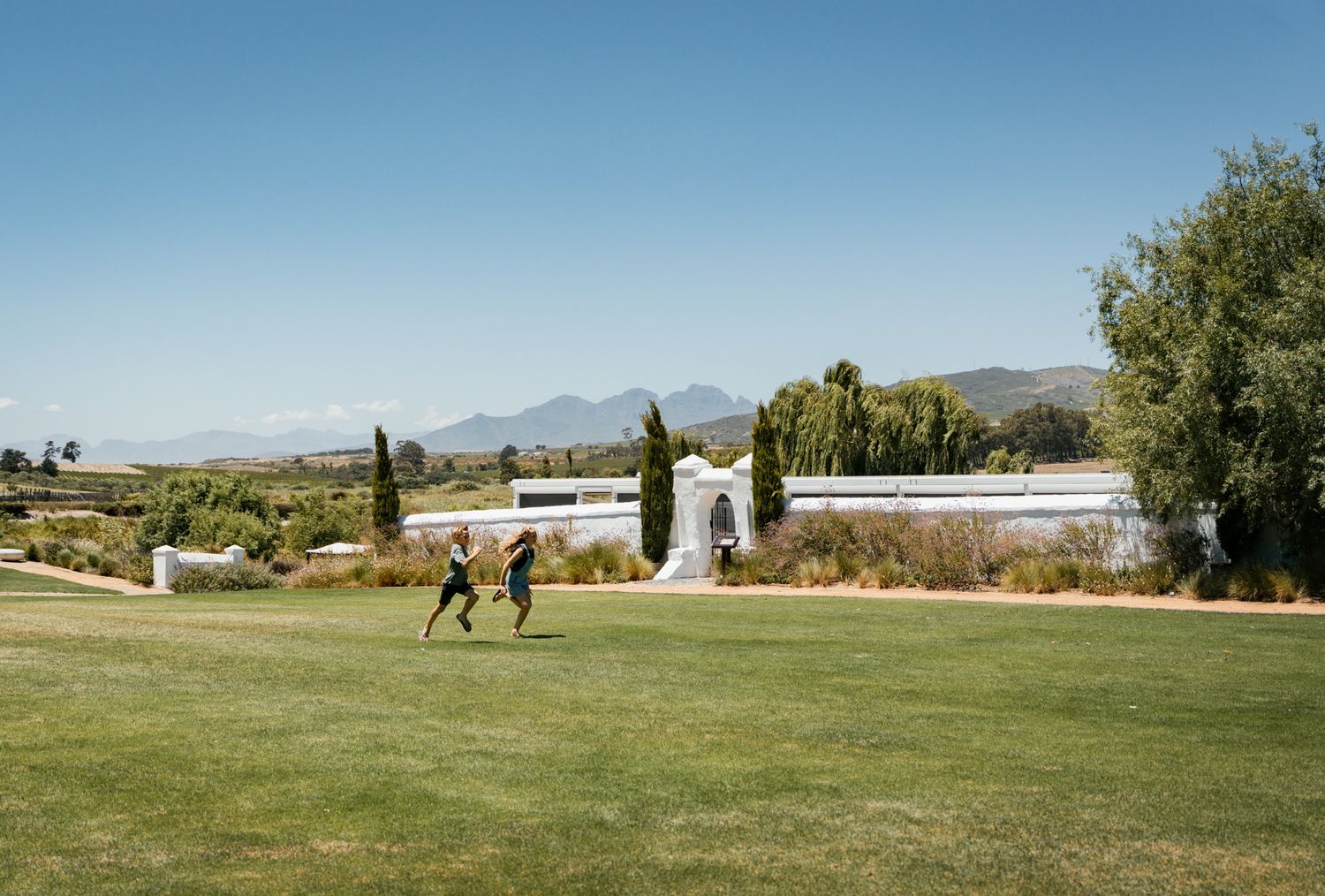 Panoramic view of a green golf course with mountains in the background.