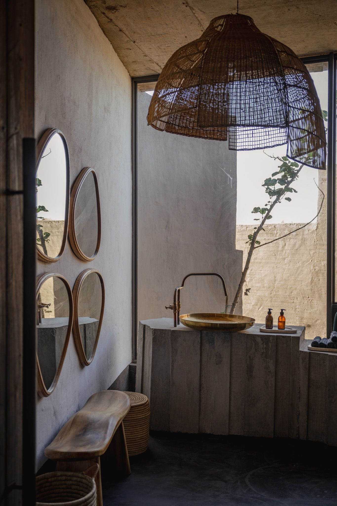 Minimalist bathroom with round mirrors, woven pendant lights, and wooden vanity.
