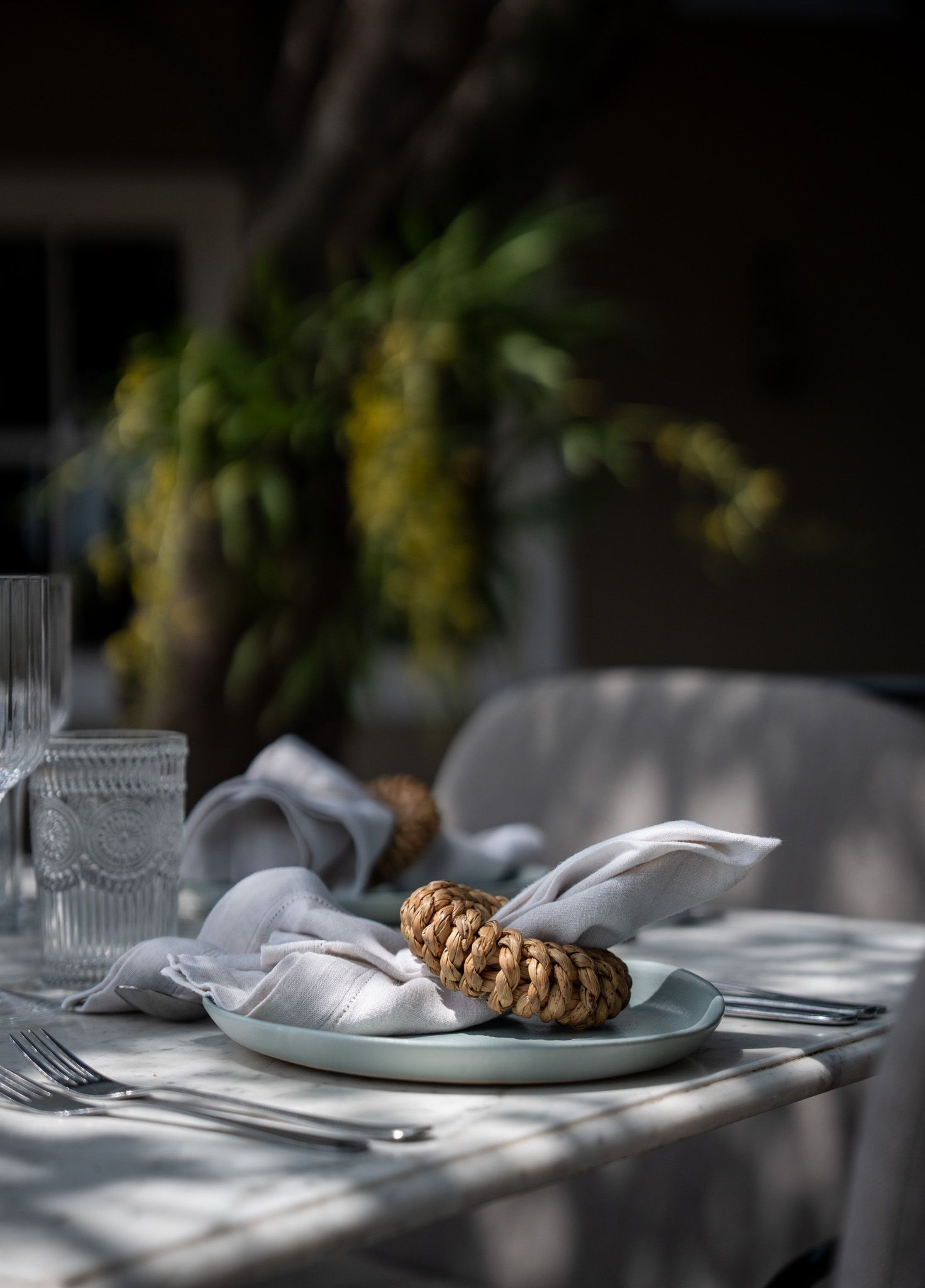 Elegant table setting with woven napkin ring and crystal glassware in soft natural light.