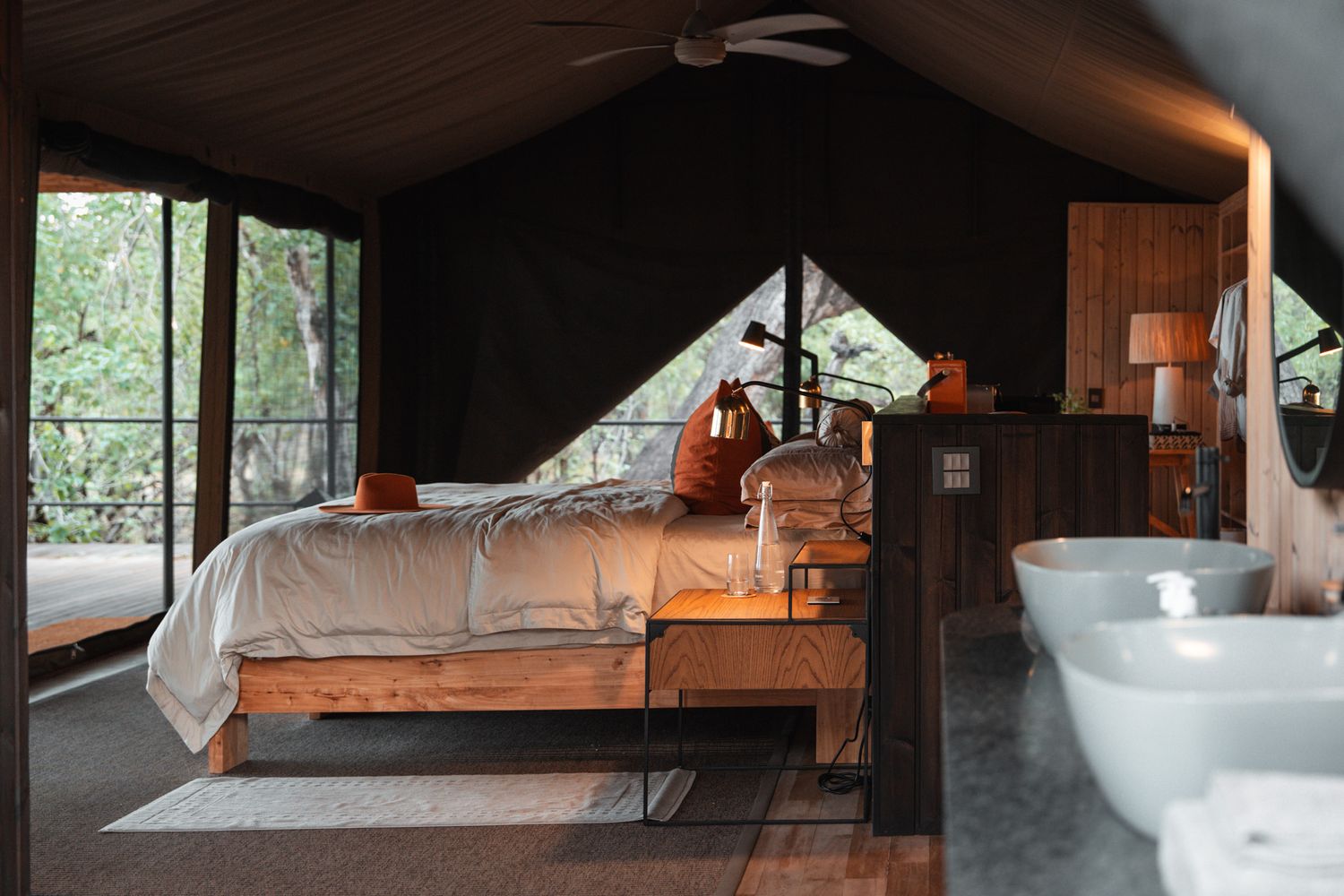 Luxurious safari-style tent interior with wooden bed frame and freestanding bathtub.