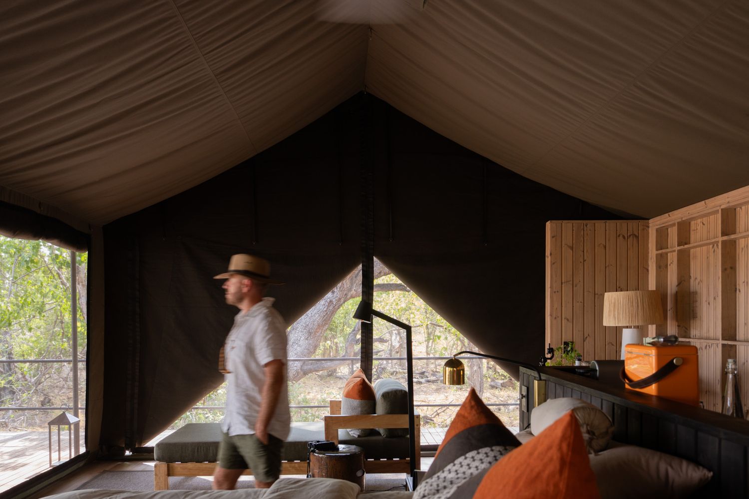 Interior view of a luxury safari tent with draped fabric ceiling and wooden furnishings.