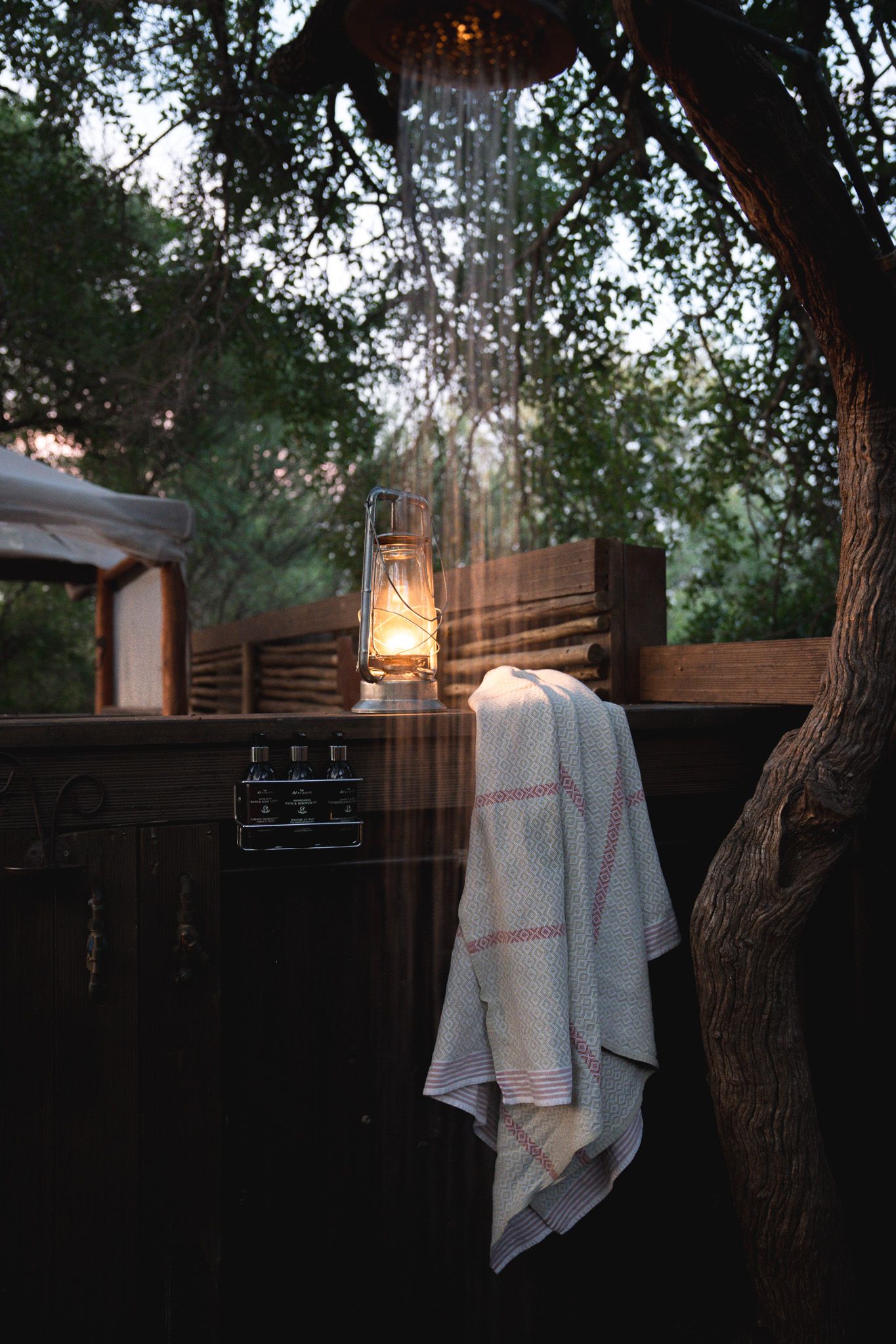 Glowing lantern hanging outdoors with white towel draped nearby at dusk.