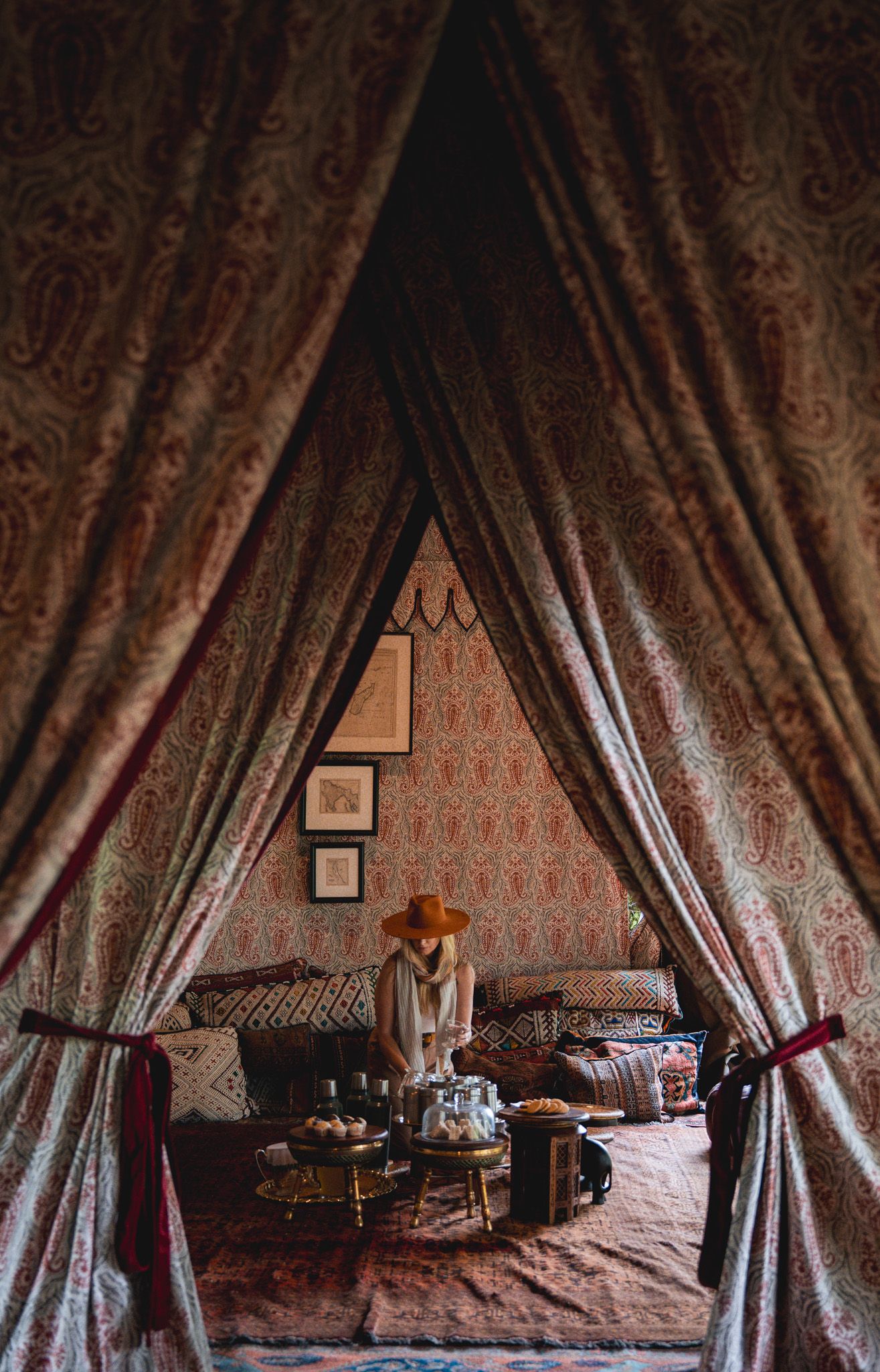 Ornate tent interior with draped curtains and vintage-style lounge setup.