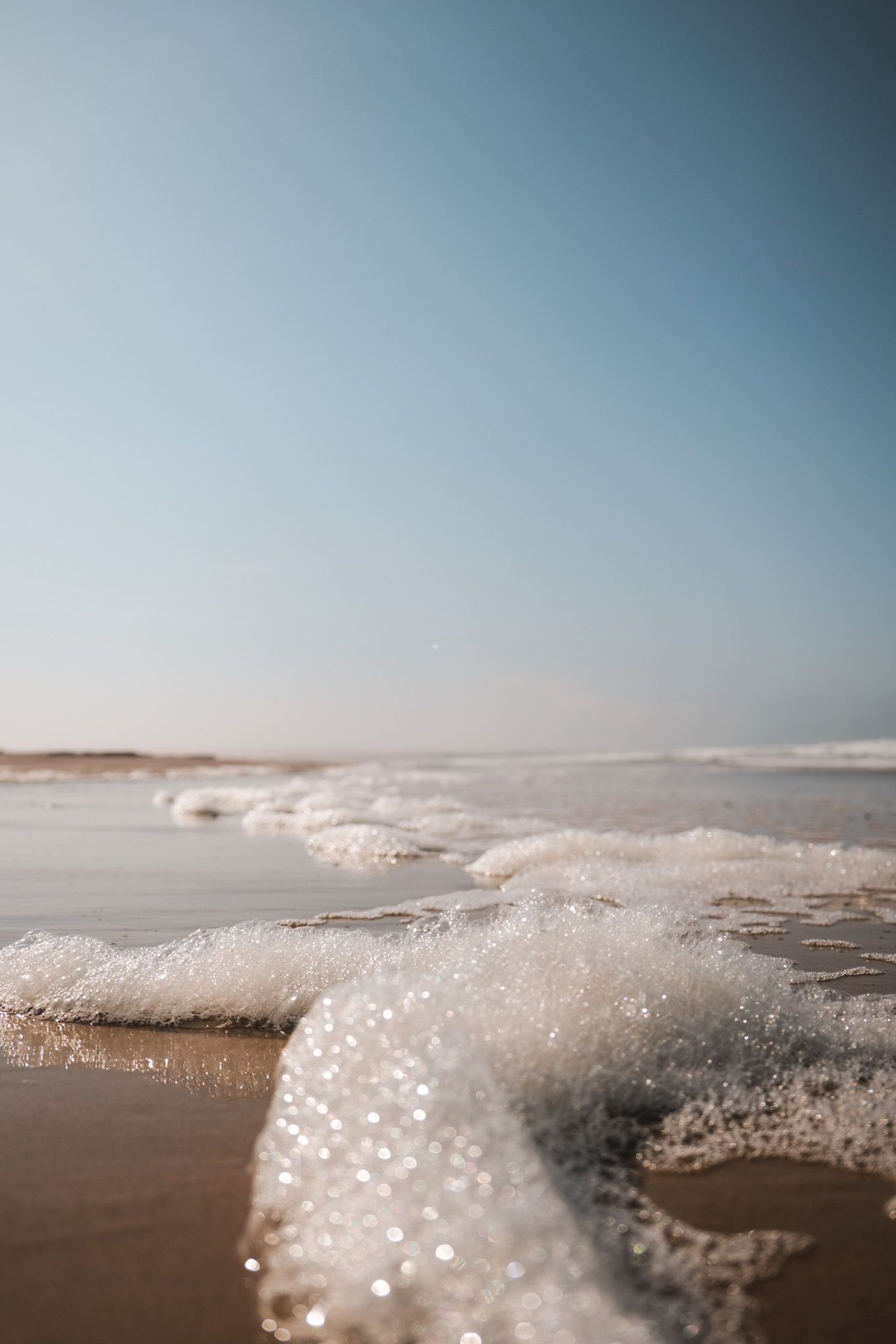 Ocean waves breaking on the shore with sparkling water droplets in the sunlight.