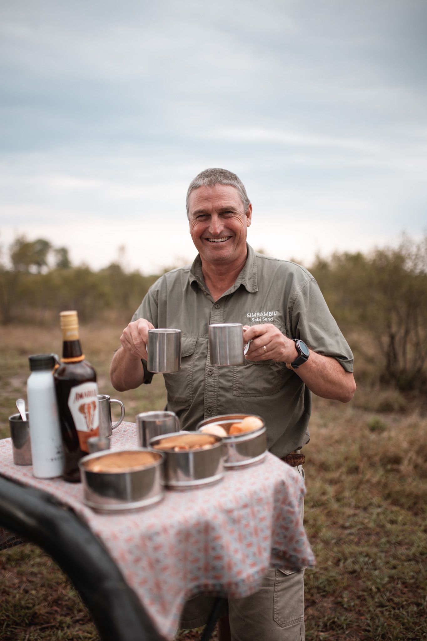 Outdoor breakfast setup with table and refreshments in a natural safari setting.