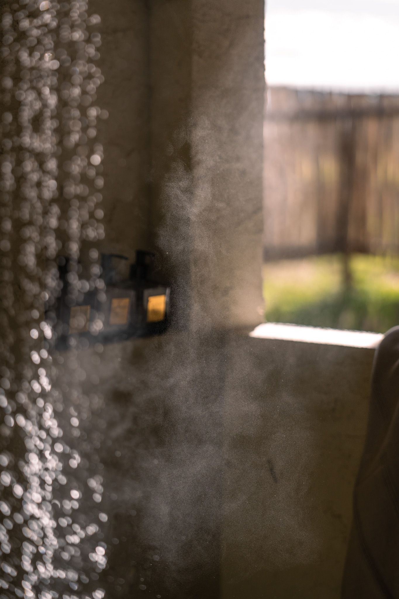 Sunlight streams through a frosted window creating dramatic shadows and mist in a cozy interior space.