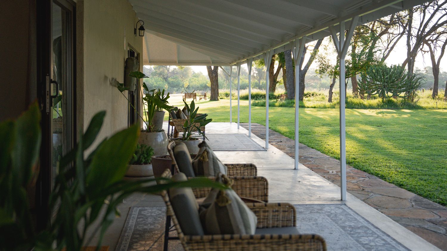 Covered outdoor walkway with wooden posts leading through a landscaped garden area.