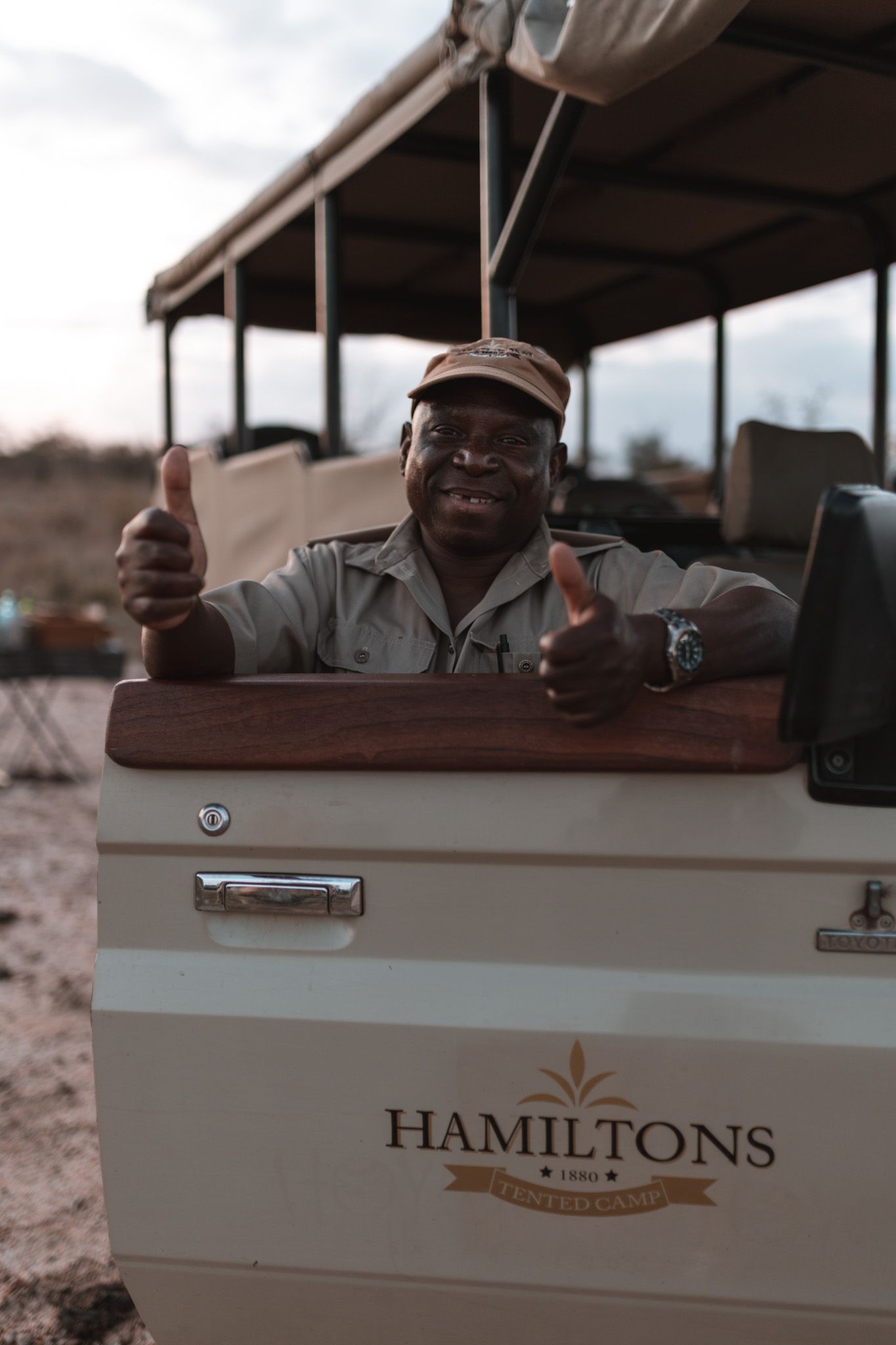 Safari vehicle with Hamilton's logo and passengers enjoying a game drive viewing experience.