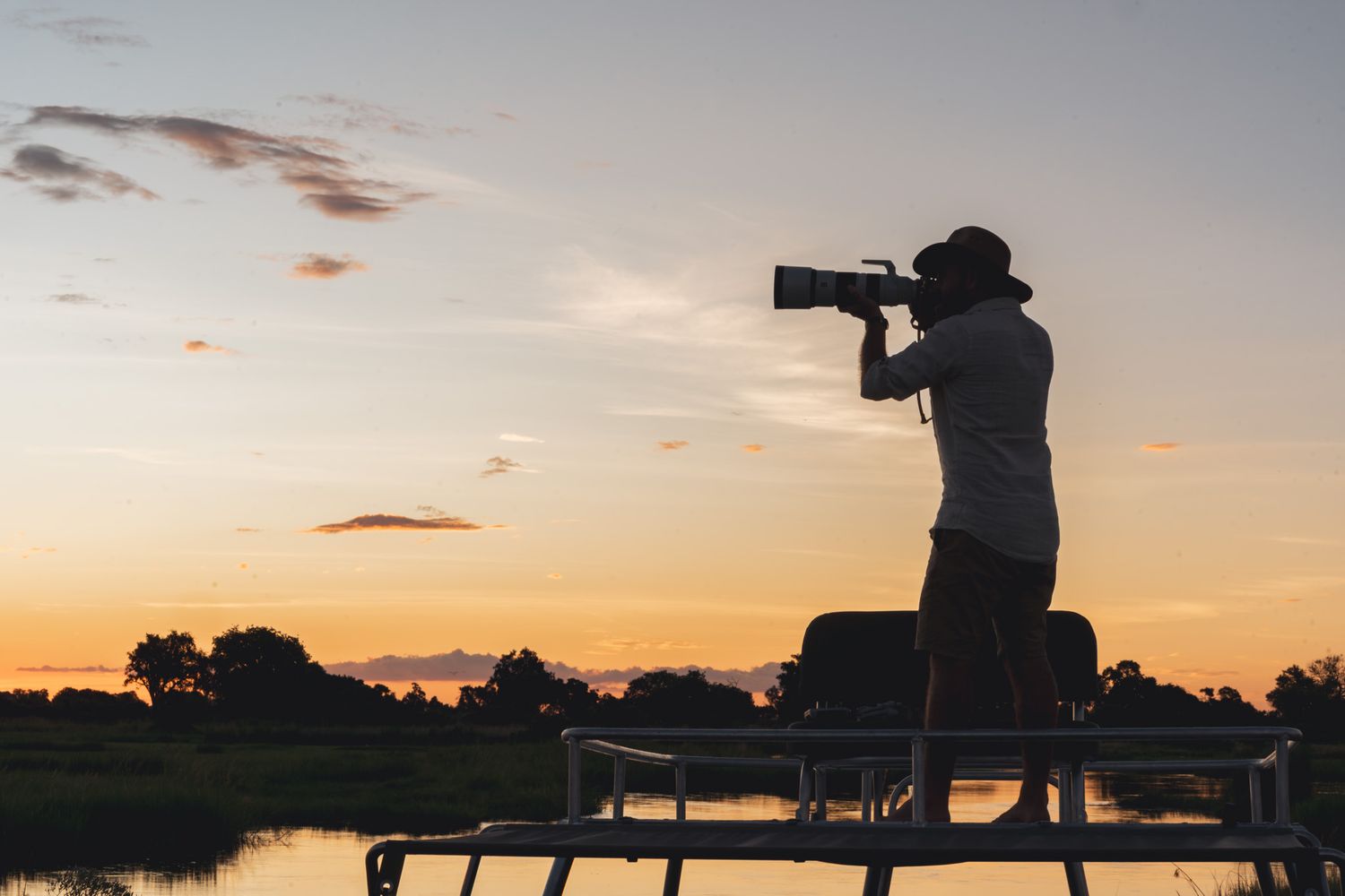Silhouettes of camera equipment and photographers against a dramatic sunset sky.