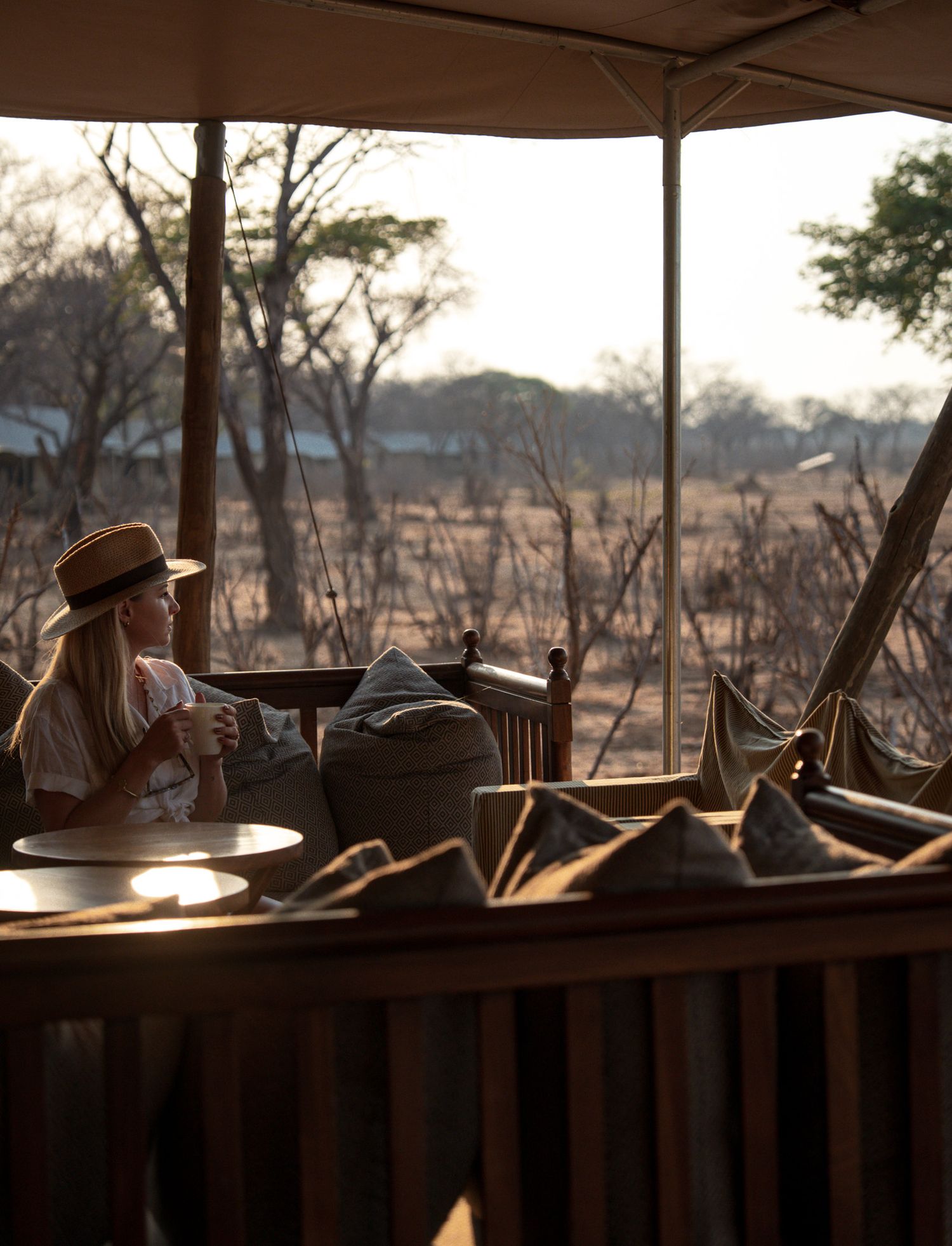 A cozy safari tent interior with a view of the savanna at dusk.