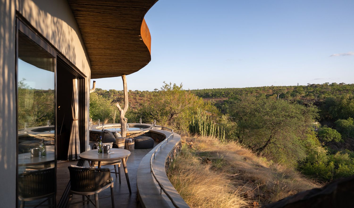 Panoramic view of an outdoor deck area surrounded by natural wilderness and rolling hills.