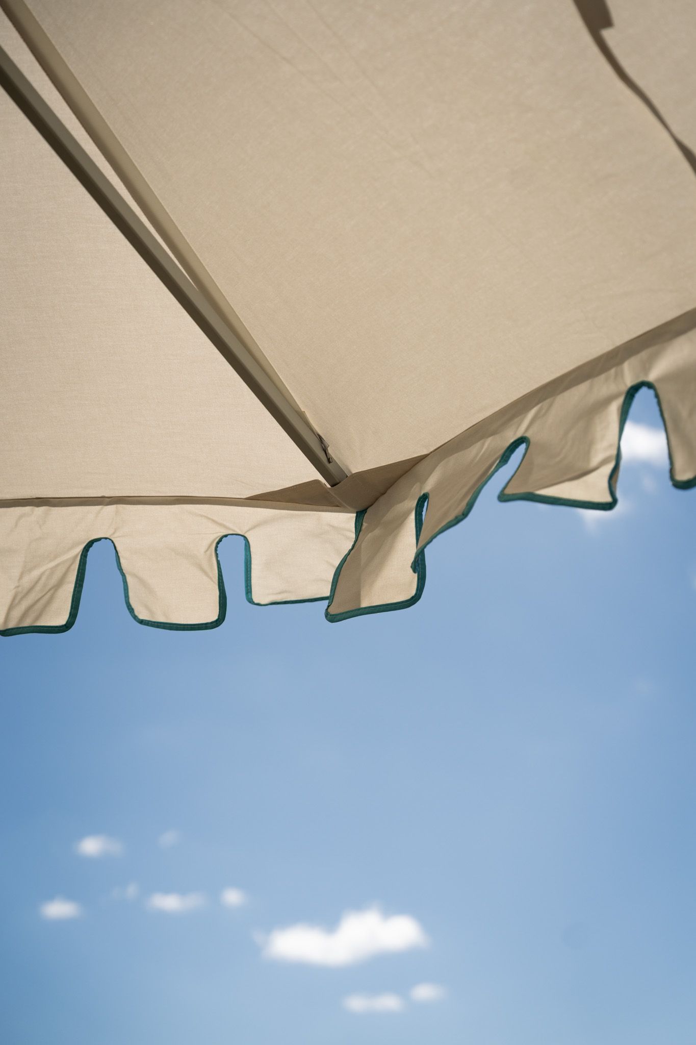 White awning against bright blue sky with fluffy clouds on a sunny day.