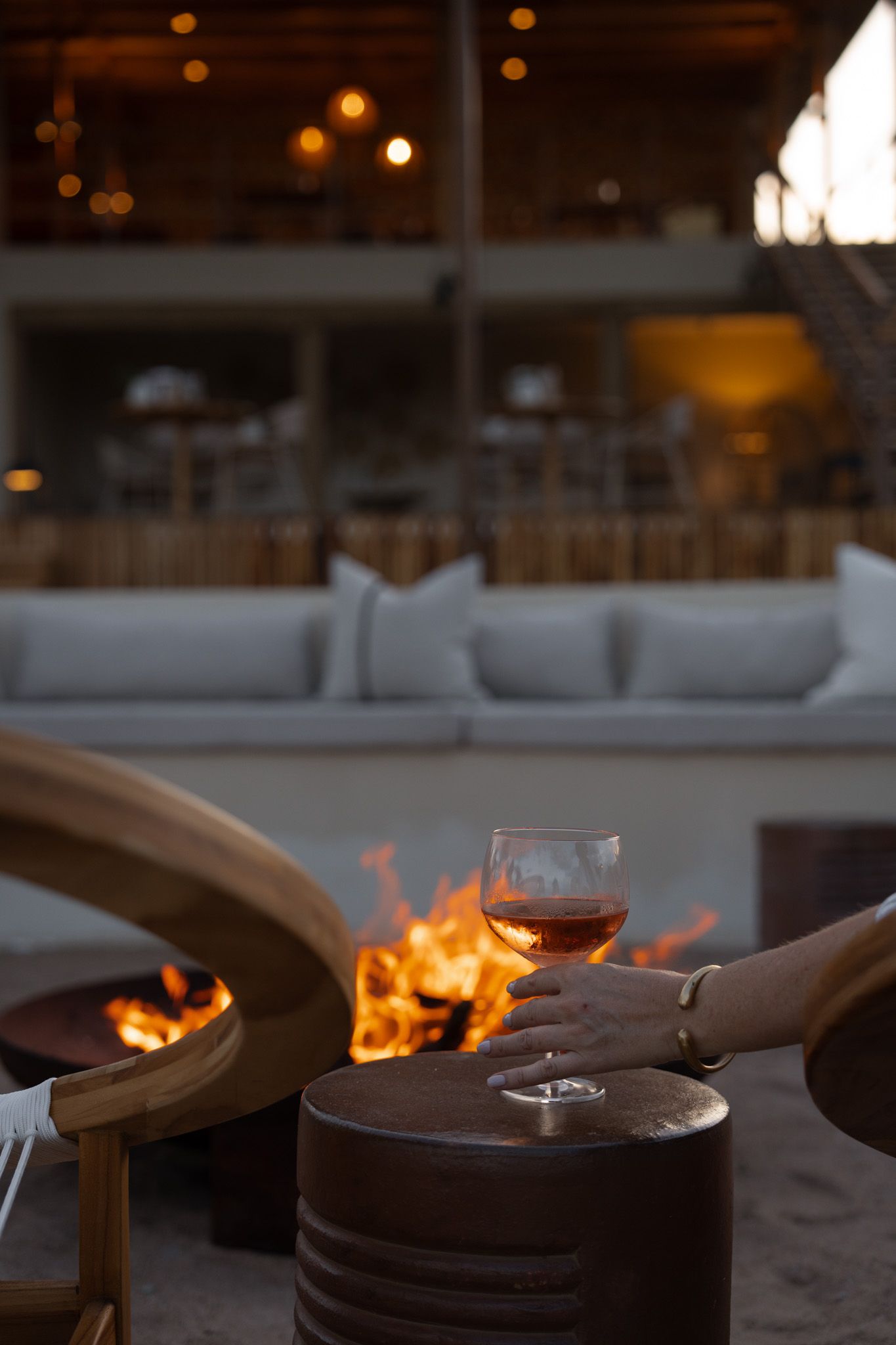Wine glass and fire pit glowing at dusk on an outdoor patio setting.