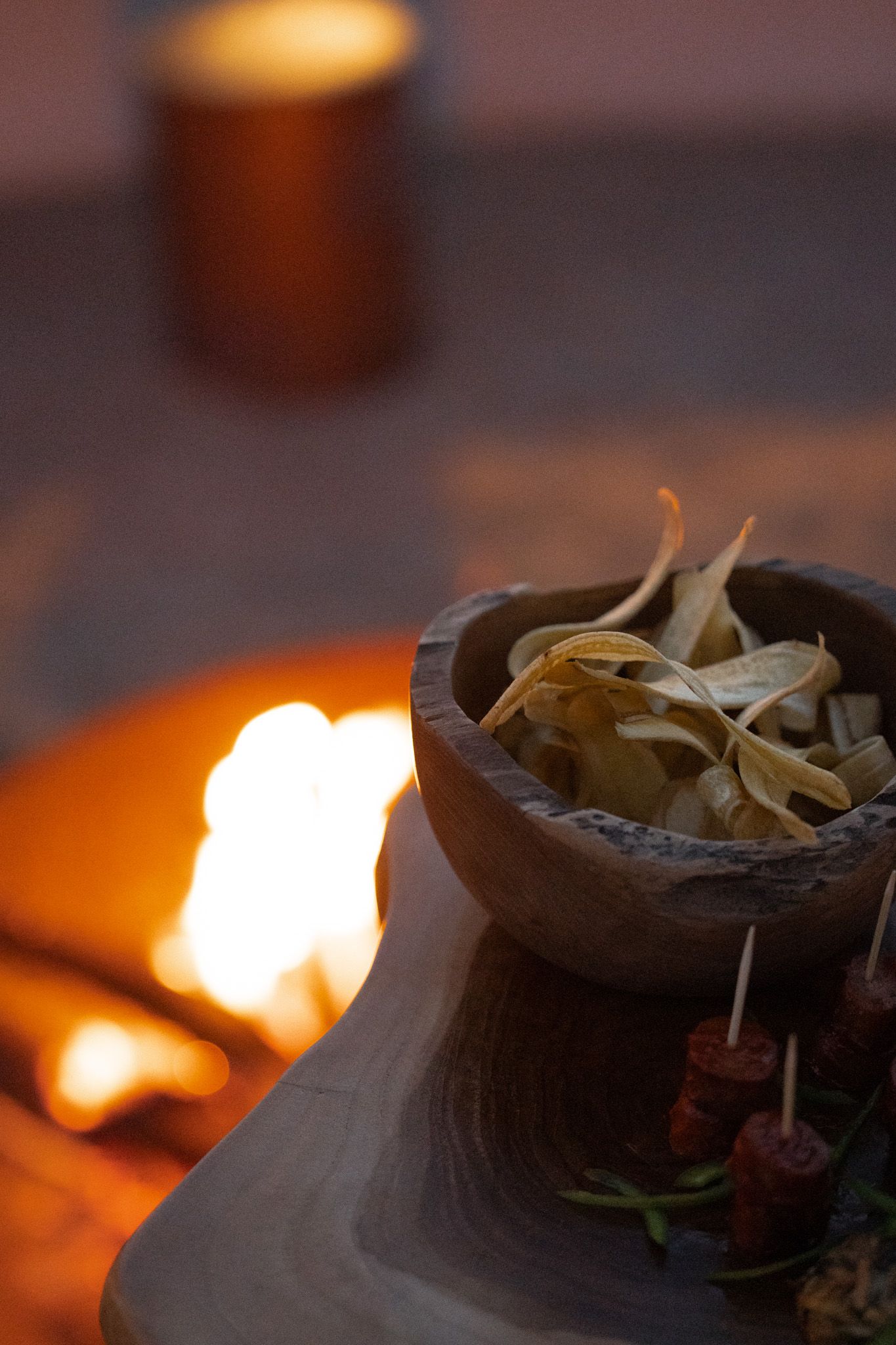Clay pot with dried herbs illuminated by firelight in dark ambient setting.