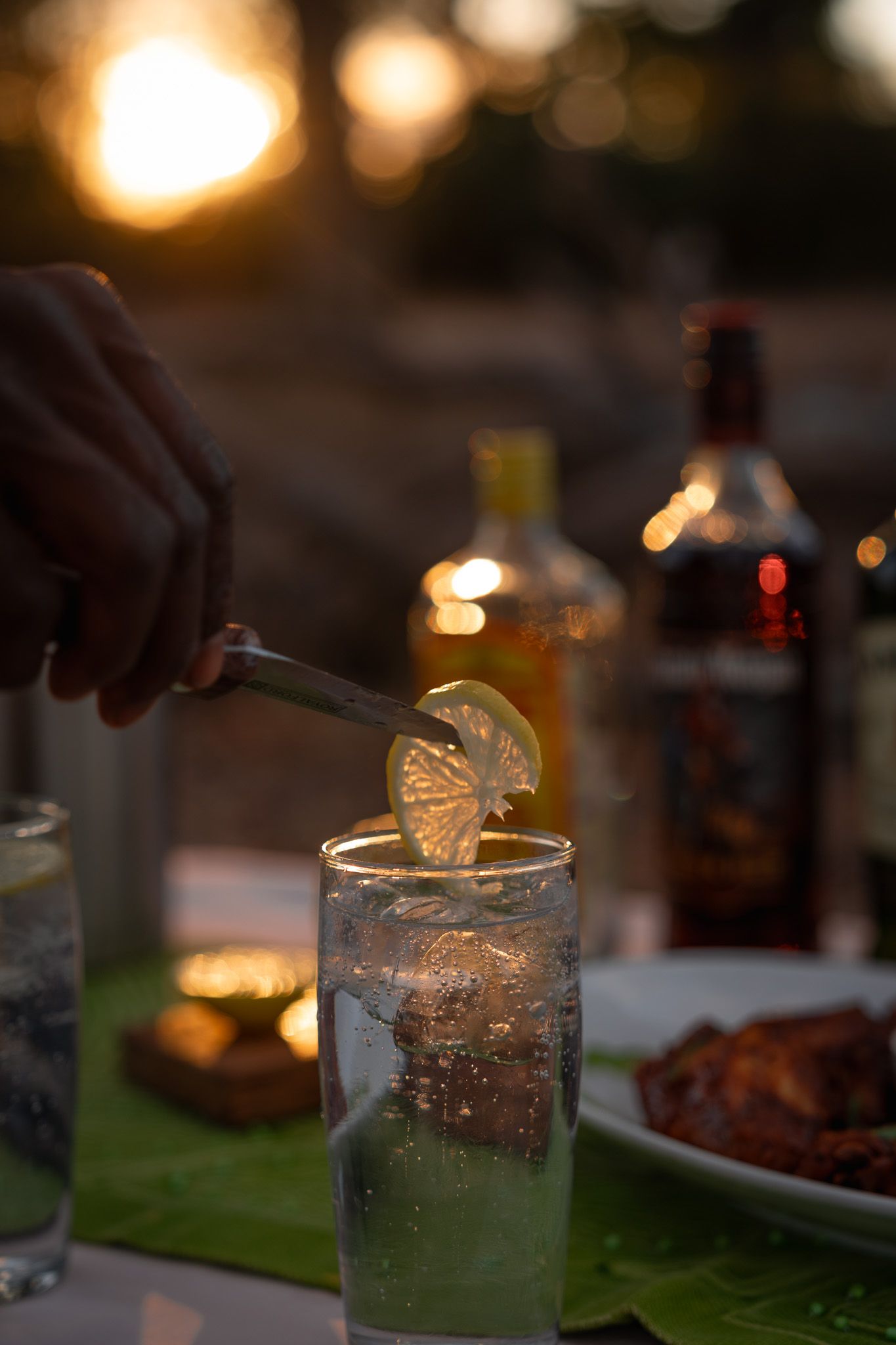 Glasses of cocktails with citrus garnishes in warm evening lighting.