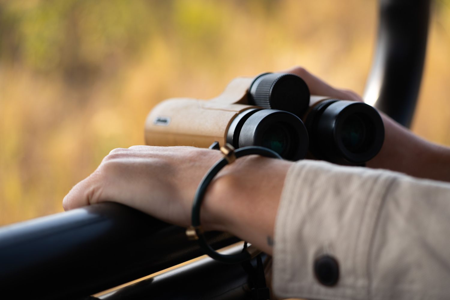 Binoculars rest on a vehicle armrest during a safari expedition.