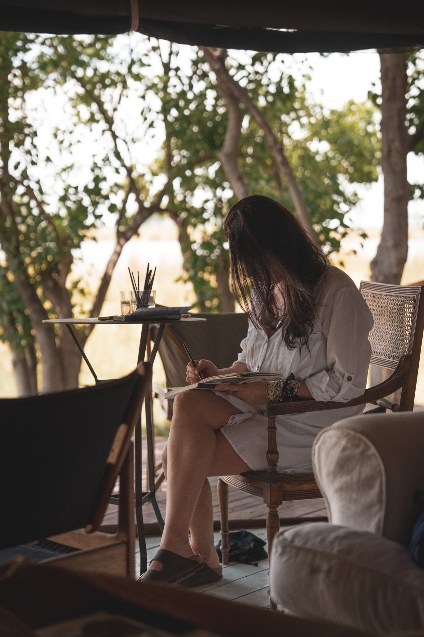 People relaxing and reading in a shaded outdoor lounge area during daytime.