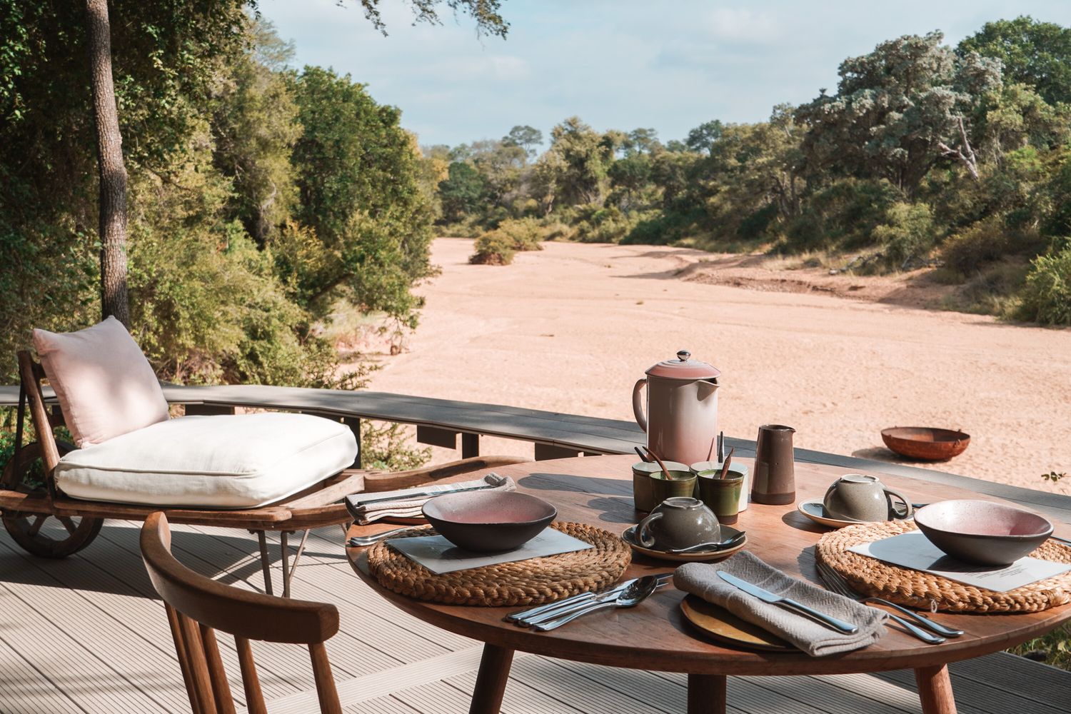 Outdoor restaurant seating with place settings overlooking natural landscape.