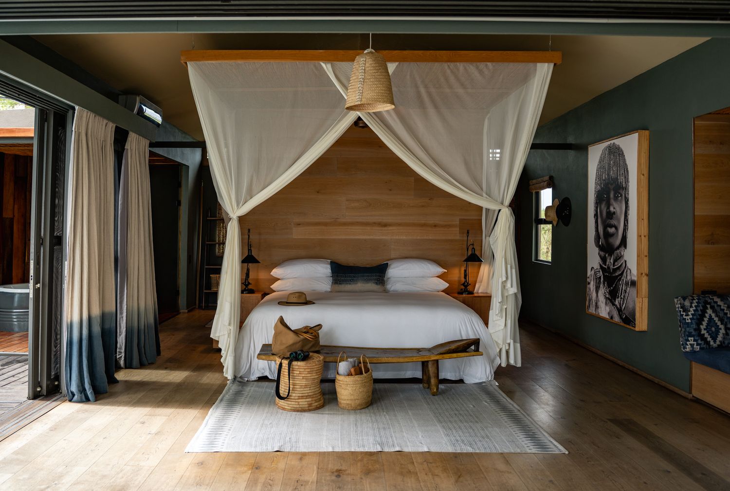 Panoramic view of an elegant bedroom with white canopy beds and wooden floors.