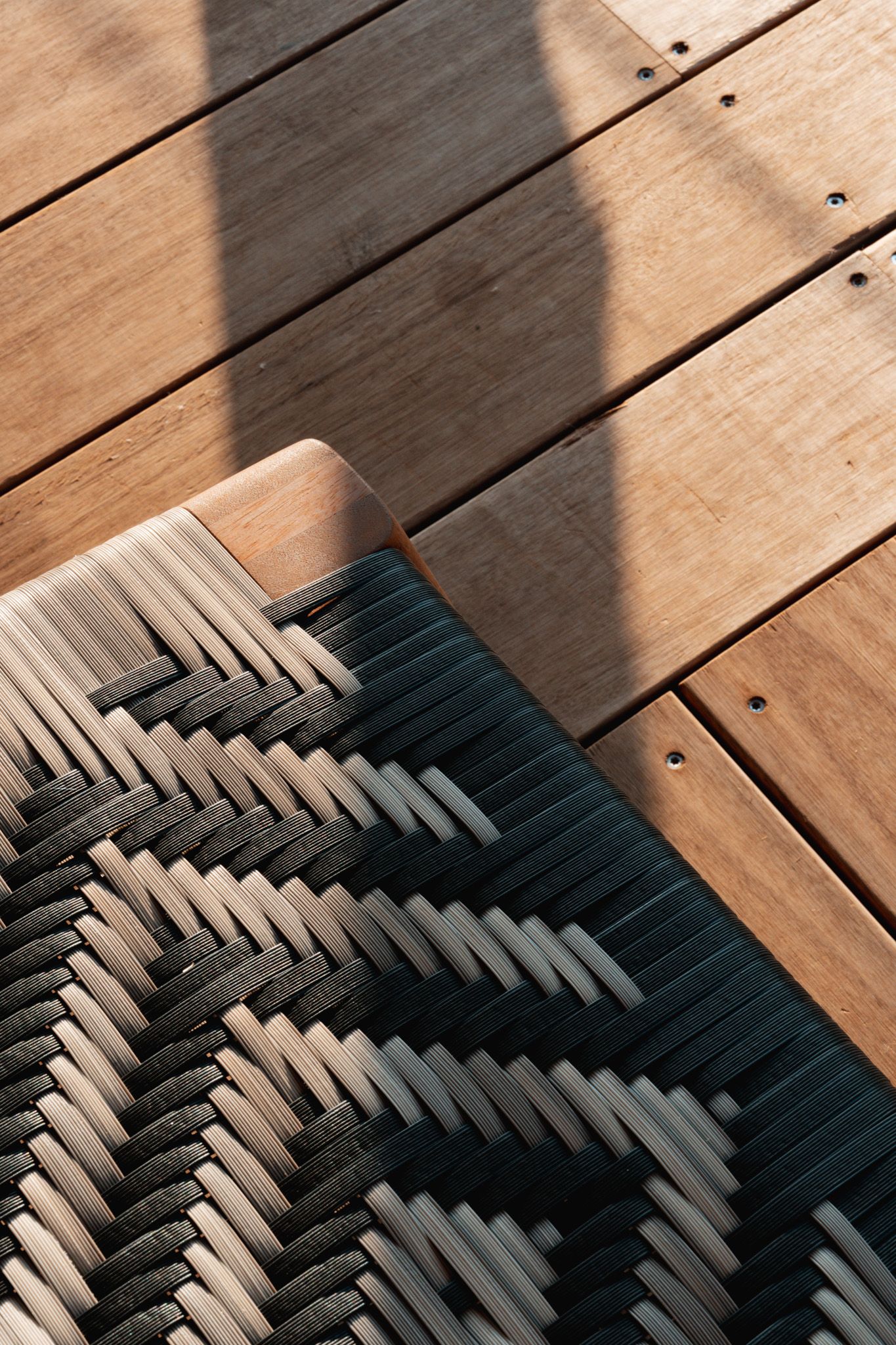Geometric pattern cushion creating dramatic shadows on wooden deck planks.
