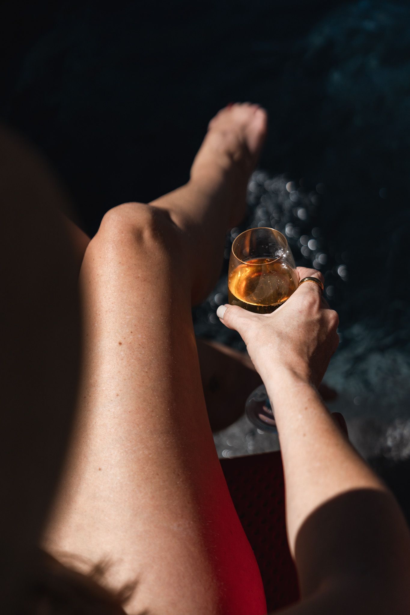 Hands holding steaming hot beverage in glass cup against dark background.