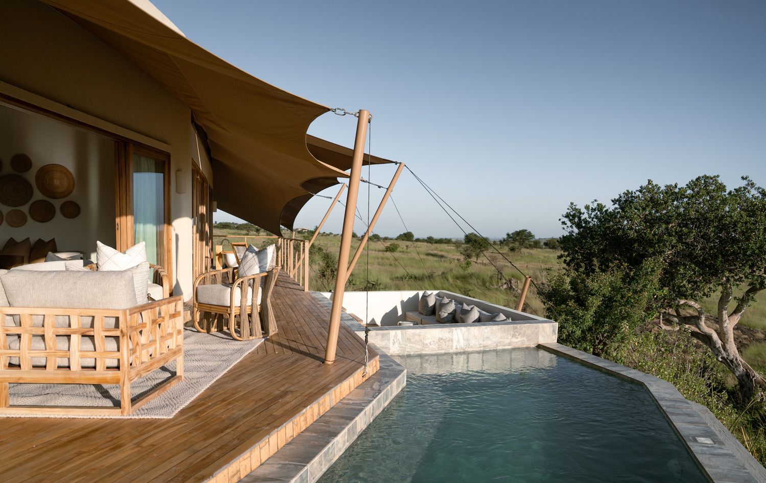 Modern safari lodge deck with infinity pool overlooking expansive grassland vista.
