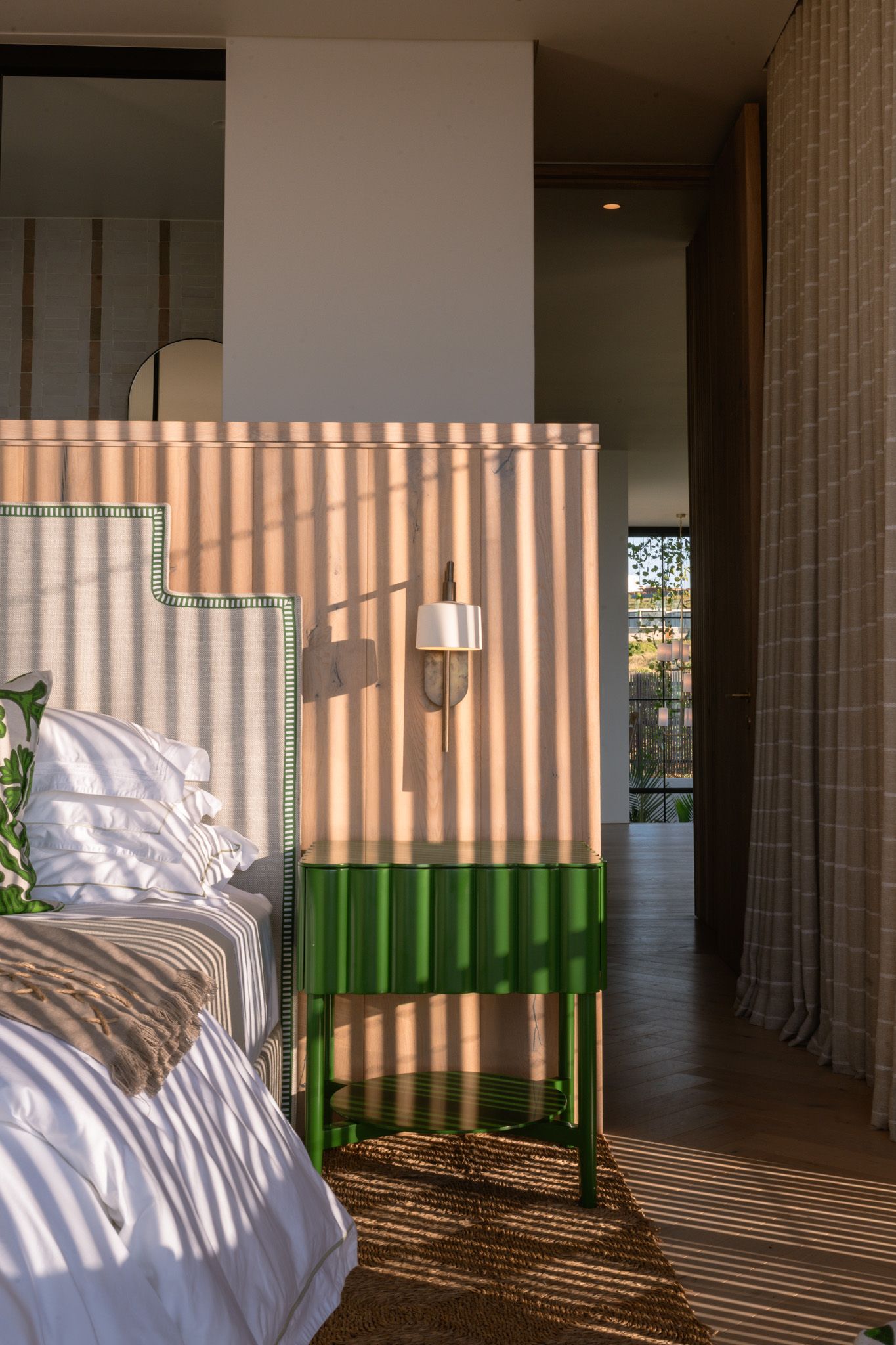 Modern bedroom interior with striped wall patterns and green bedside table casting dramatic shadows.
