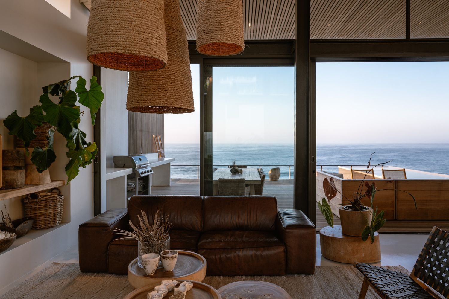 Coastal living room with panoramic ocean views, natural fiber pendant lights, and modern furnishings.